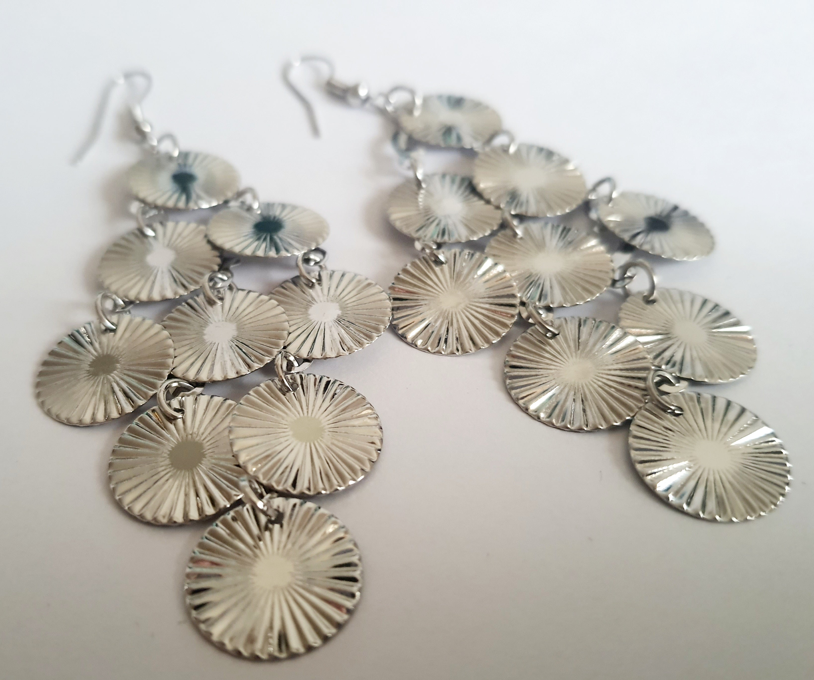 Srebrne kolczyki wiszące z promienistych dysków na biglu, wykonane ze stali nierdzewnej. Lekka, ruchoma forma z błyszczącym wykończeniem. Styl glamour i elegancja. Rouge Bizu.

