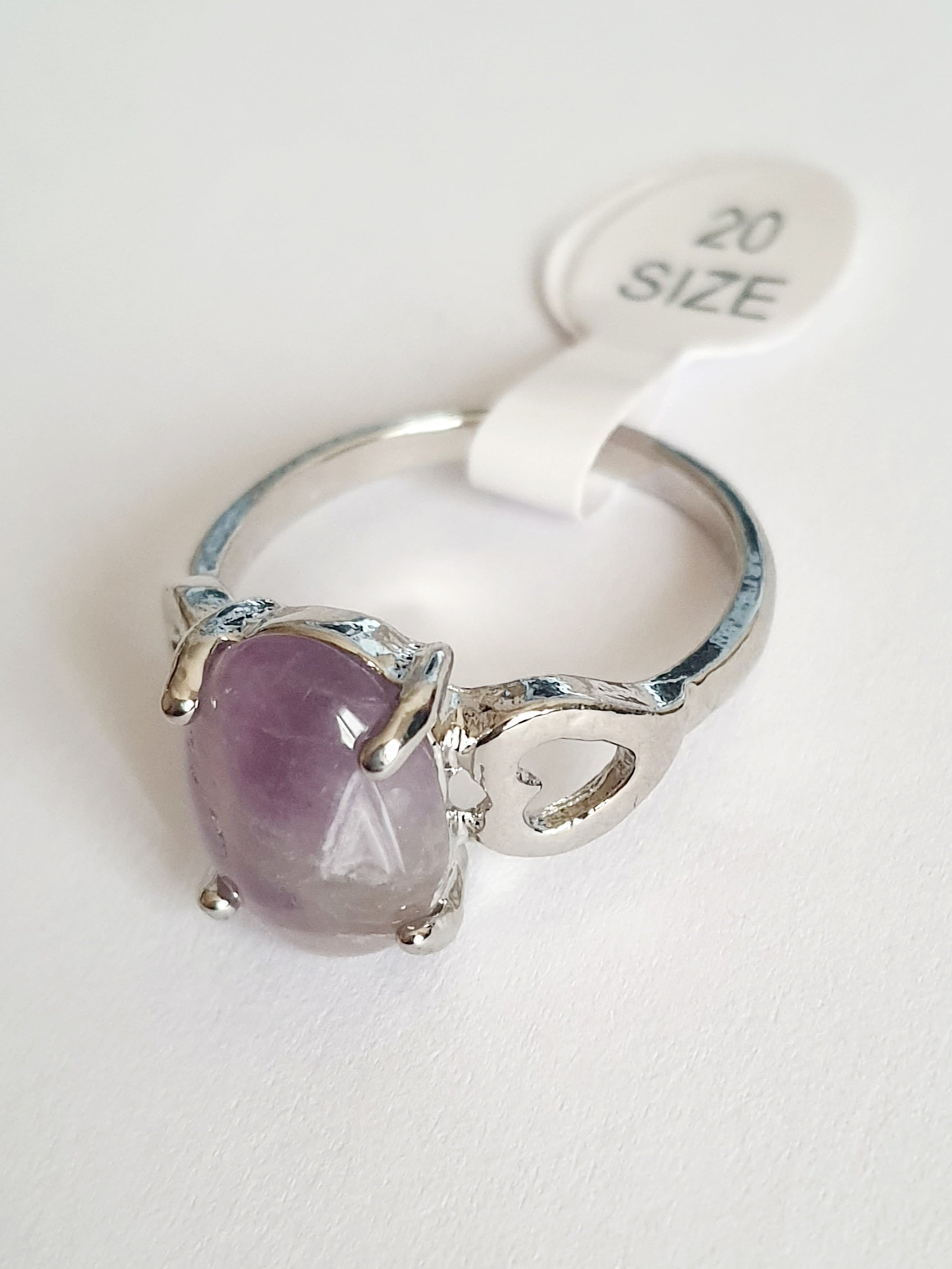 Srebrny pierścionek ze stali nierdzewnej z owalnym kamieniem w odcieniu lila i ozdobnym wycięciem po bokach. Styl romantyczny, artystyczny. Rozmiar 20 mm. Rouge Bizu.

