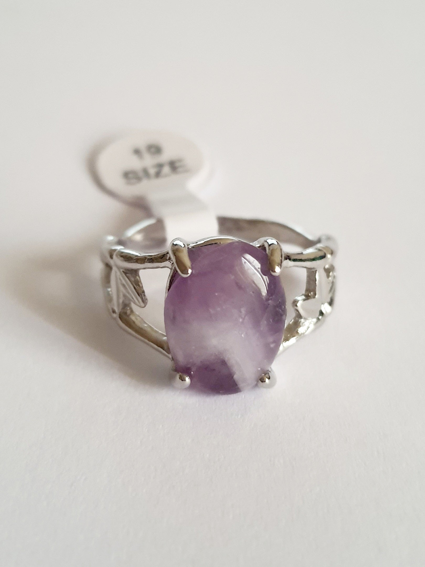 Srebrny pierścionek z fioletowym kamieniem przypominającym ametyst, w romantycznym stylu. Stal chirurgiczna, delikatne metalowe zdobienia przypominające gałązki. Rozmiar 19 mm. Rouge Bizu.

