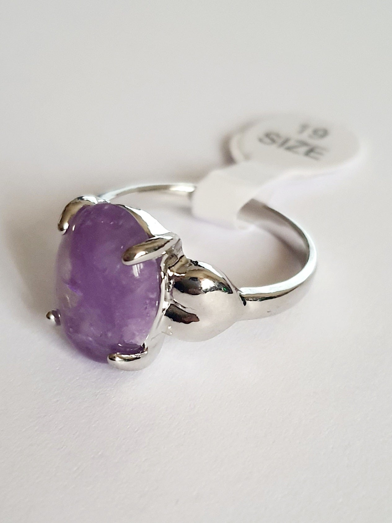 Pierścionek ze stali chirurgicznej z lawendowym kamieniem, owalnym kaboszonem i oprawą w formie liści. Styl vintage i naturalna elegancja. Rozmiar 19 mm. Rouge Bizu.

