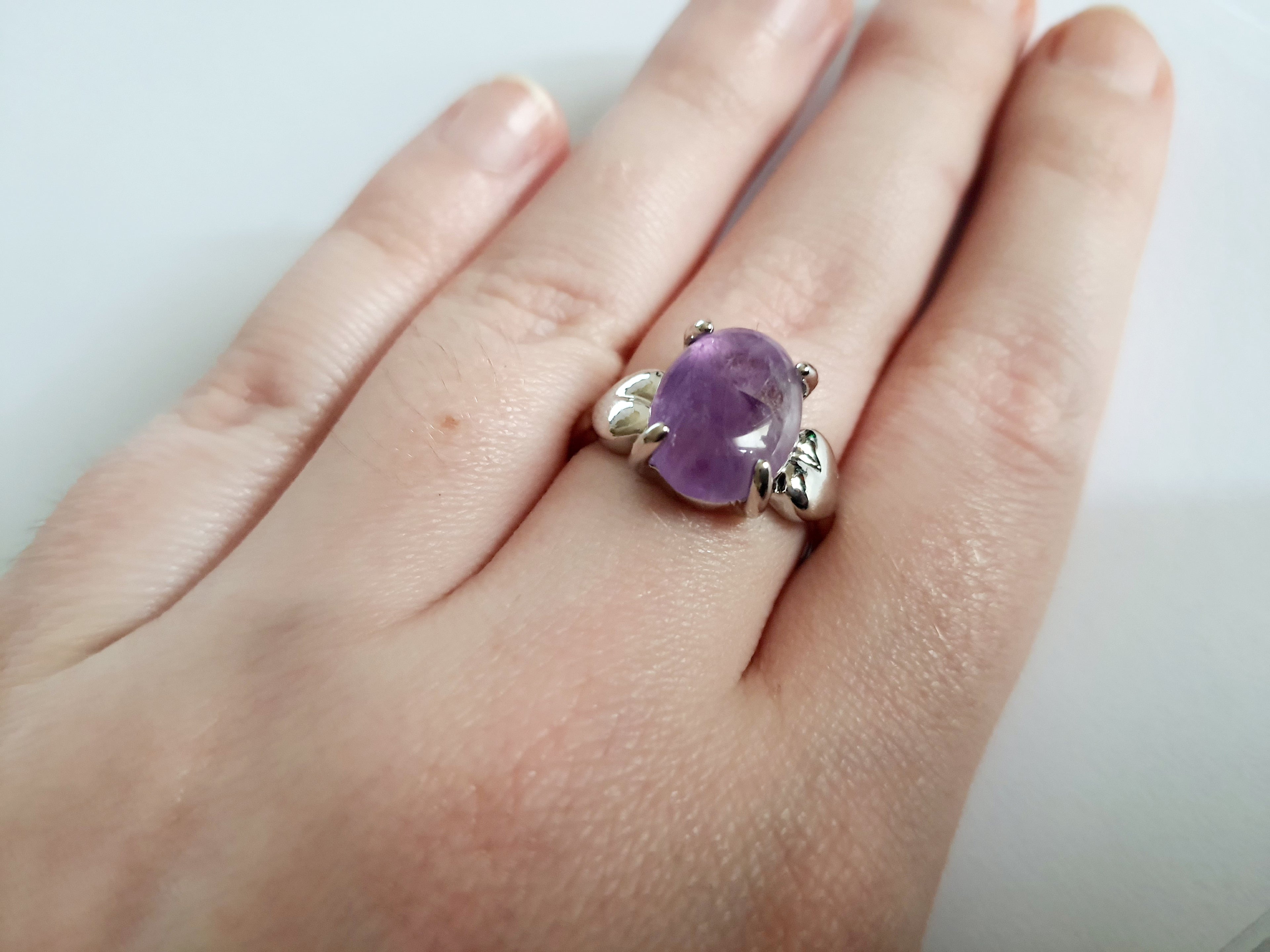 Pierścionek ze stali chirurgicznej z lawendowym kamieniem, owalnym kaboszonem i oprawą w formie liści. Styl vintage i naturalna elegancja. Rozmiar 19 mm. Rouge Bizu.

