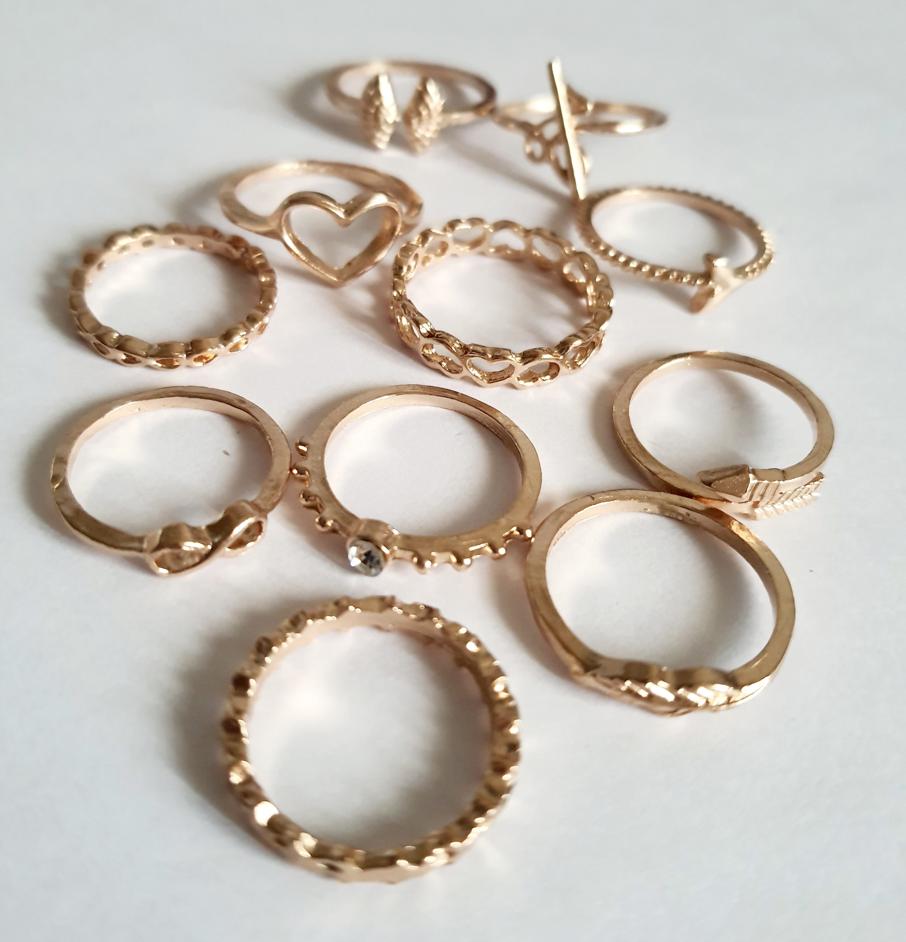 Zestaw 11 złotych pierścionków ze stali nierdzewnej i chirurgicznej w stylu minimalistycznym, z motywami serca, strzałki i skrzydeł, rozmiary od 16 mm do 20 mm. Wodoodporne, hipoalergiczne, jakość premium. Rouge Bizu.