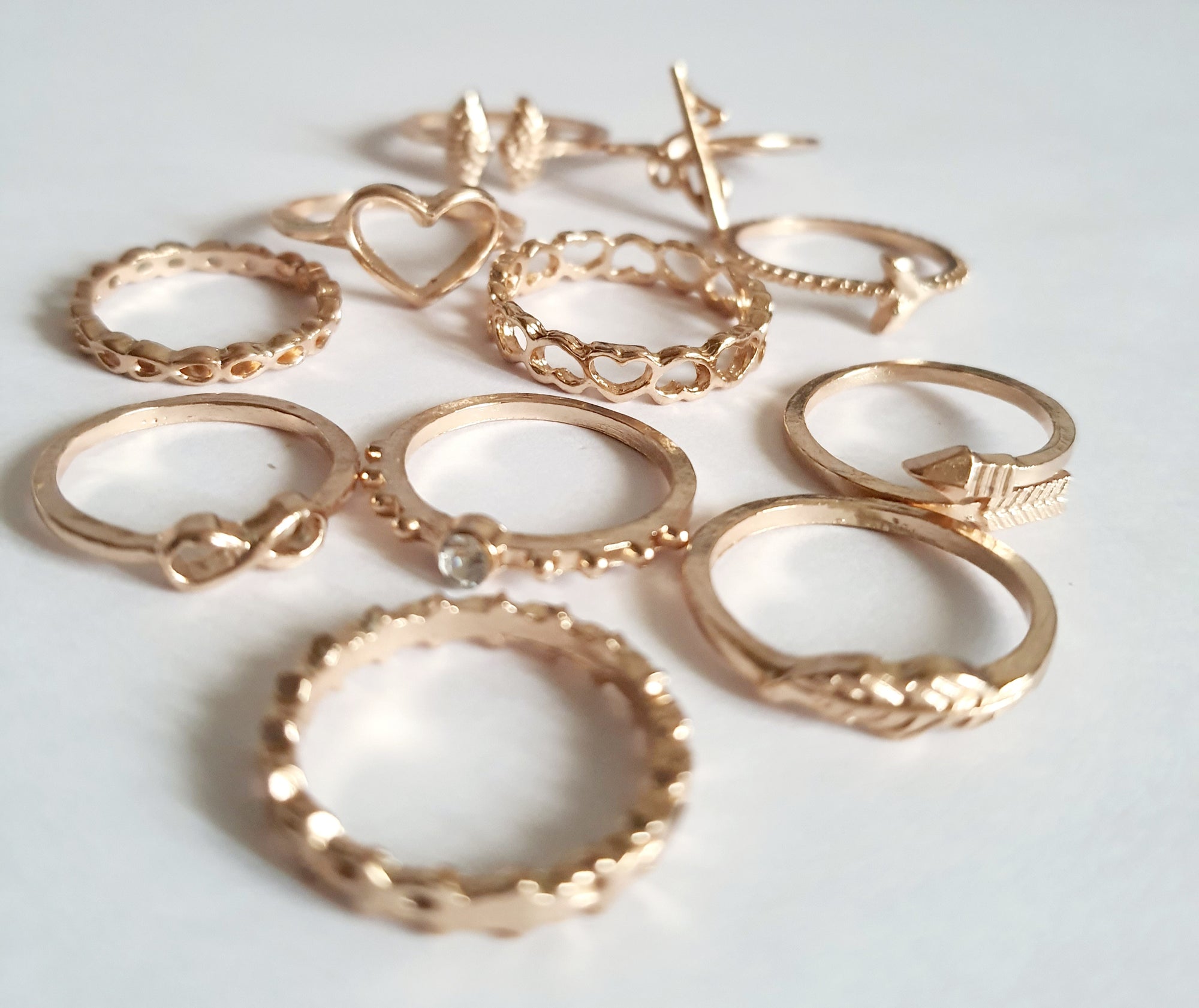 Zestaw 11 złotych pierścionków ze stali nierdzewnej i chirurgicznej w stylu minimalistycznym, z motywami serca, strzałki i skrzydeł, rozmiary od 16 mm do 20 mm. Wodoodporne, hipoalergiczne, jakość premium. Rouge Bizu.