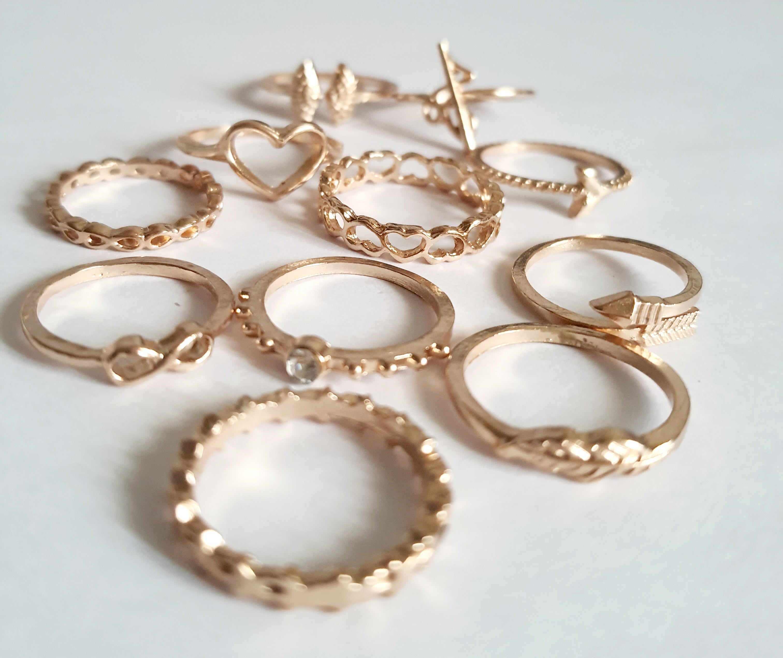 Zestaw 11 złotych pierścionków ze stali nierdzewnej i chirurgicznej w stylu minimalistycznym, z motywami serca, strzałki i skrzydeł, rozmiary od 16 mm do 20 mm. Wodoodporne, hipoalergiczne, jakość premium. Rouge Bizu.