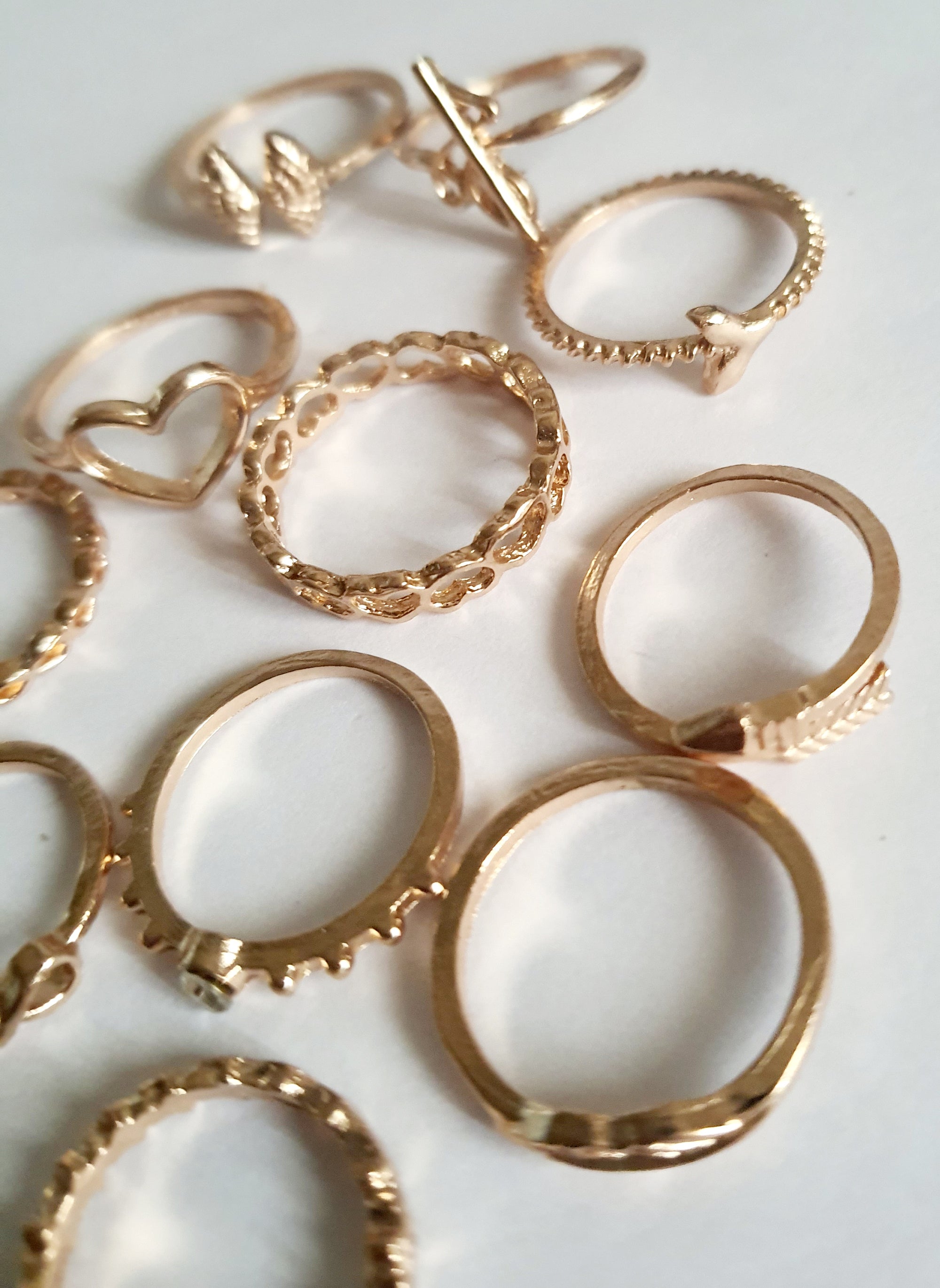 Zestaw 11 złotych pierścionków ze stali nierdzewnej i chirurgicznej w stylu minimalistycznym, z motywami serca, strzałki i skrzydeł, rozmiary od 16 mm do 20 mm. Wodoodporne, hipoalergiczne, jakość premium. Rouge Bizu.