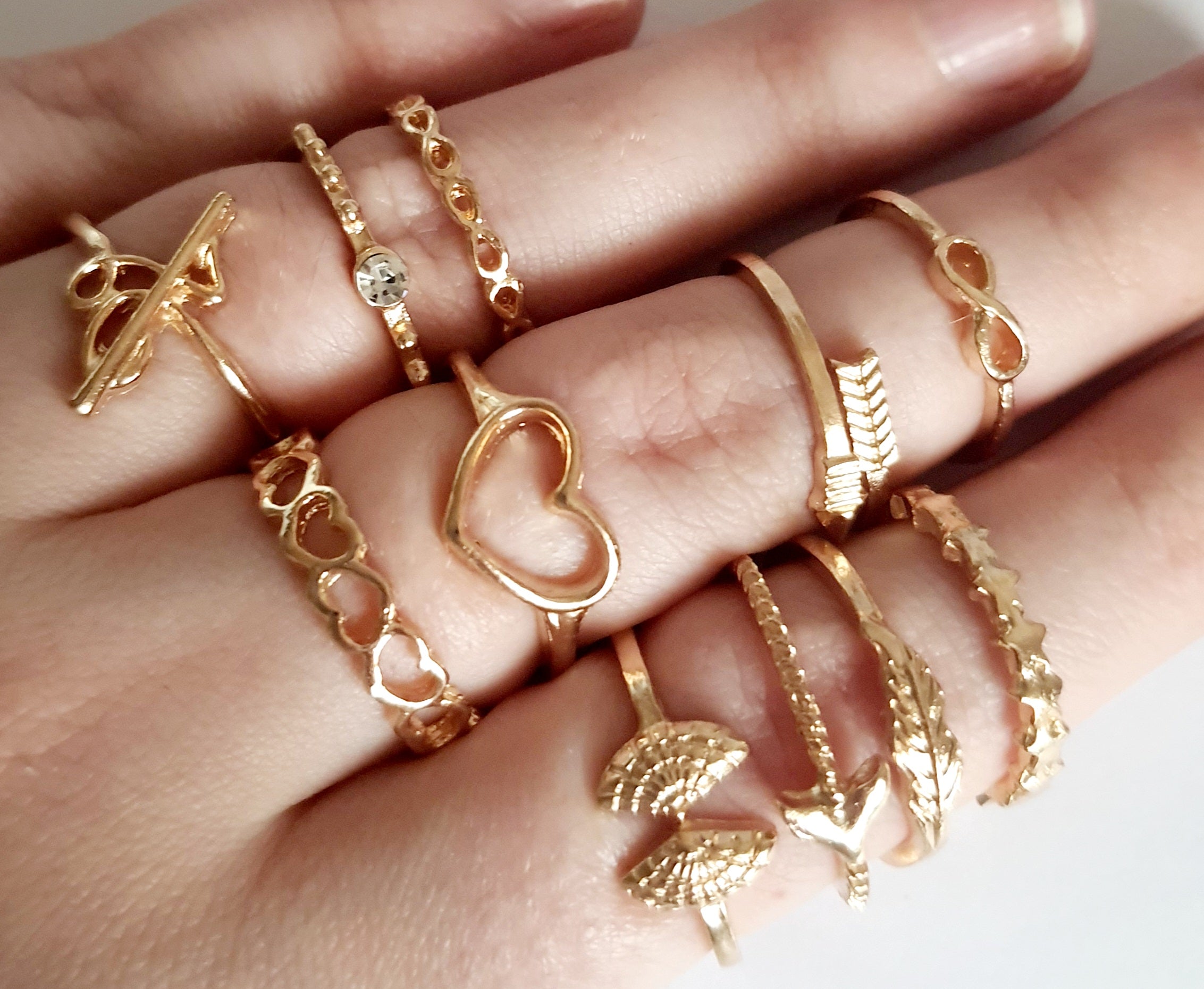 Zestaw 11 złotych pierścionków ze stali nierdzewnej i chirurgicznej w stylu minimalistycznym, z motywami serca, strzałki i skrzydeł, rozmiary od 16 mm do 20 mm. Wodoodporne, hipoalergiczne, jakość premium. Rouge Bizu.