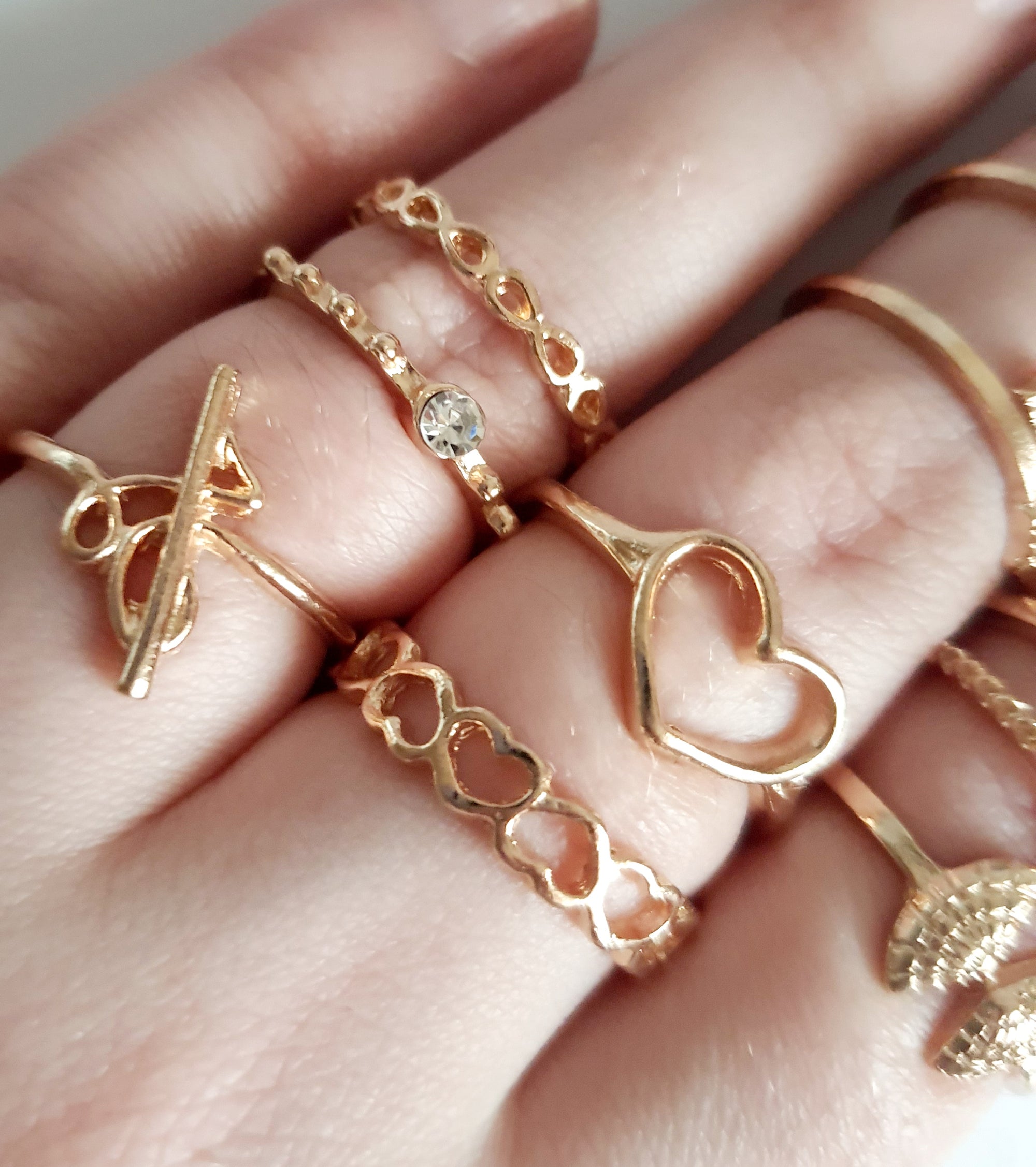 Zestaw 11 złotych pierścionków ze stali nierdzewnej i chirurgicznej w stylu minimalistycznym, z motywami serca, strzałki i skrzydeł, rozmiary od 16 mm do 20 mm. Wodoodporne, hipoalergiczne, jakość premium. Rouge Bizu.