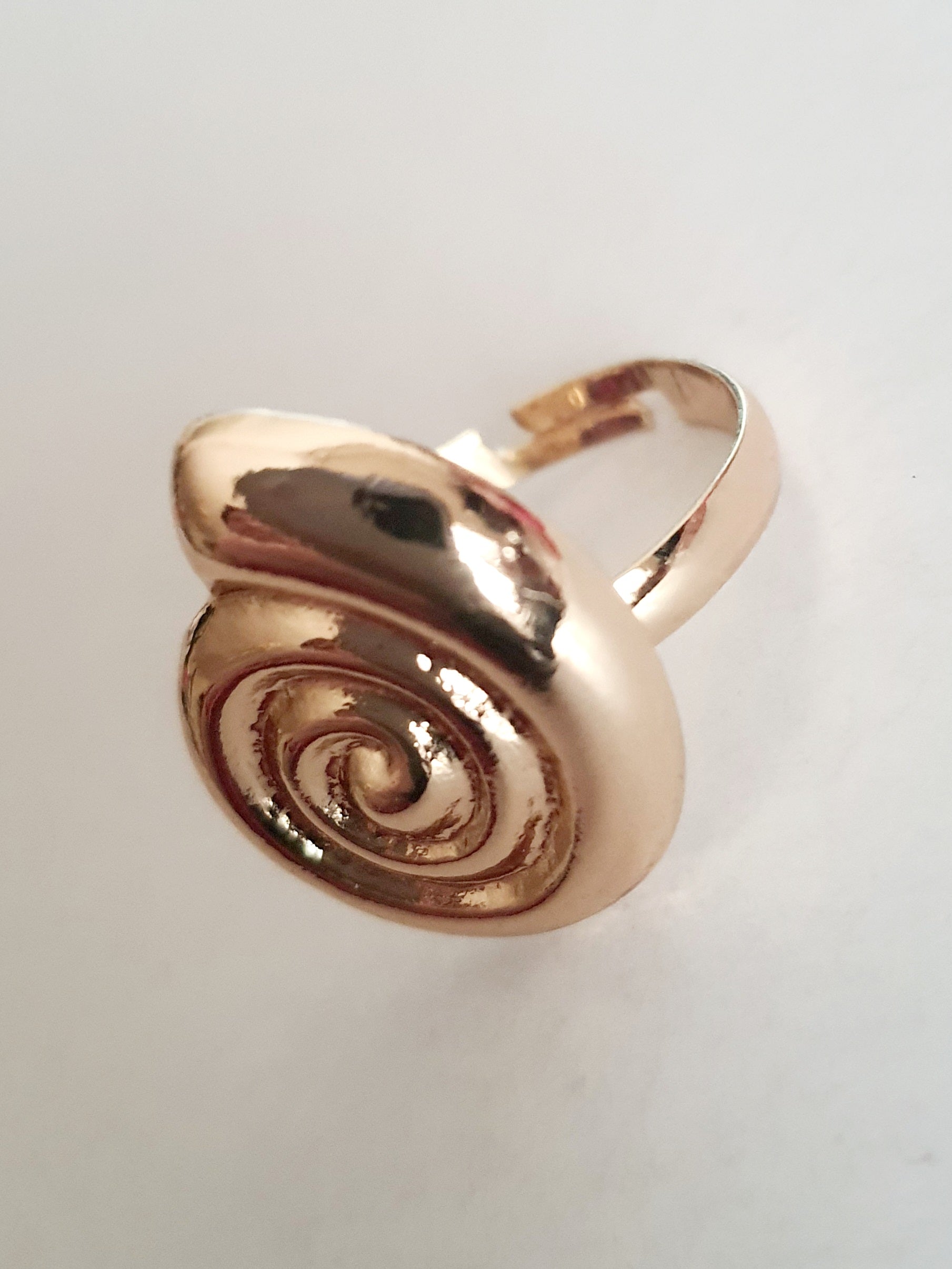 Pierścionek spiralny ze stali nierdzewnej w kolorze żółtego złota, z błyszczącym wykończeniem i efektownym, hipnotyzującym kształtem spirali. Styl minimalistyczny z nutą artystycznej ekstrawagancji. Regulowany rozmiar. Rouge Bizu.

