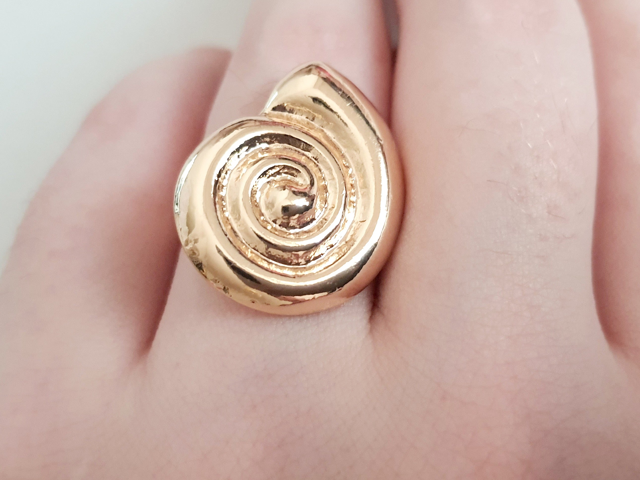 Pierścionek spiralny ze stali nierdzewnej w kolorze żółtego złota, z błyszczącym wykończeniem i efektownym, hipnotyzującym kształtem spirali. Styl minimalistyczny z nutą artystycznej ekstrawagancji. Regulowany rozmiar. Rouge Bizu.

