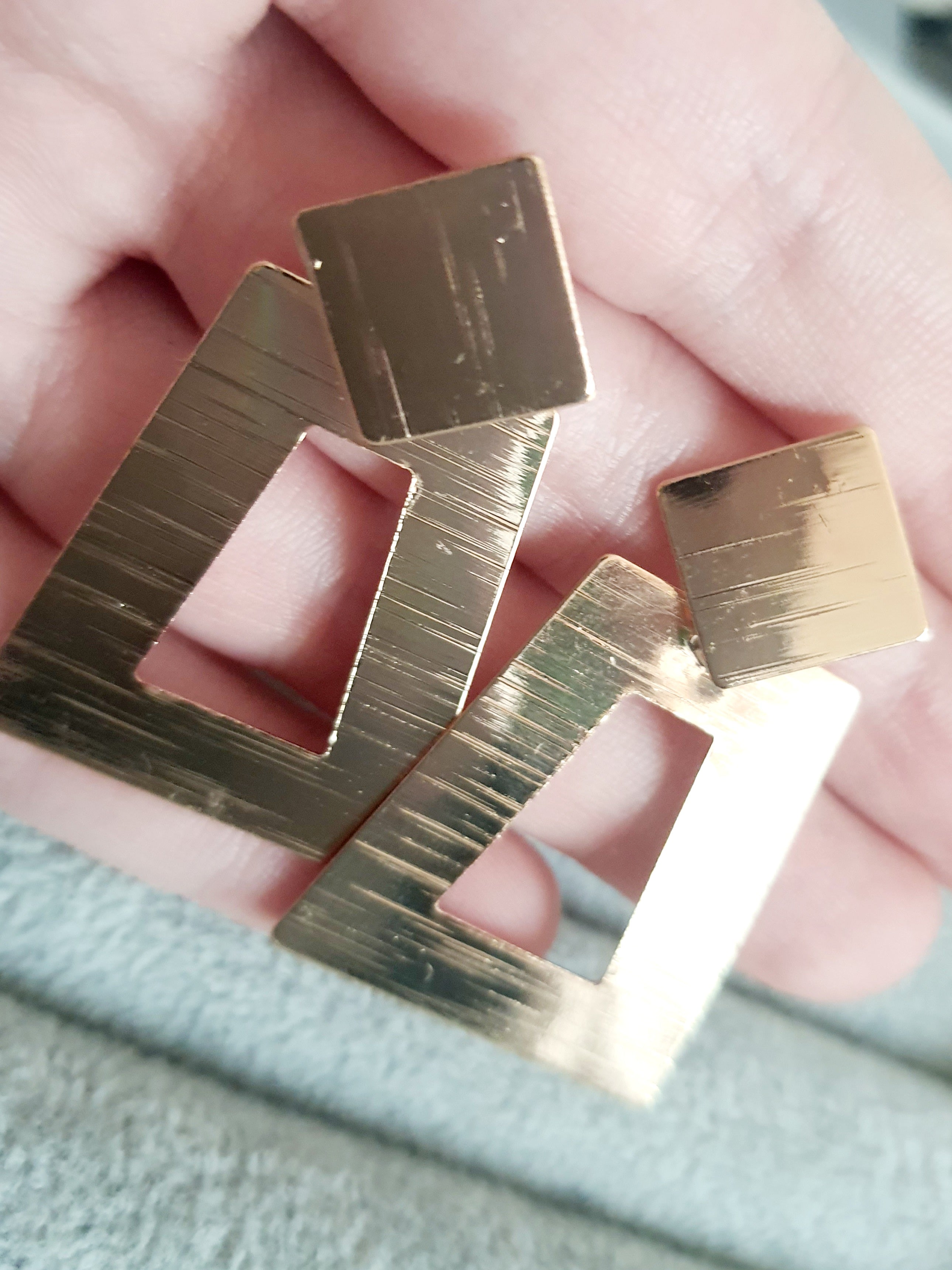 Geometryczne kolczyki z różowego złota o długości 5 cm, wykonane ze stali nierdzewnej. Trapez z wycięciem i kwadratowa baza w formie wkrętki. Nowoczesny, minimalistyczny design w stylu art deco. Rouge Bizu.

