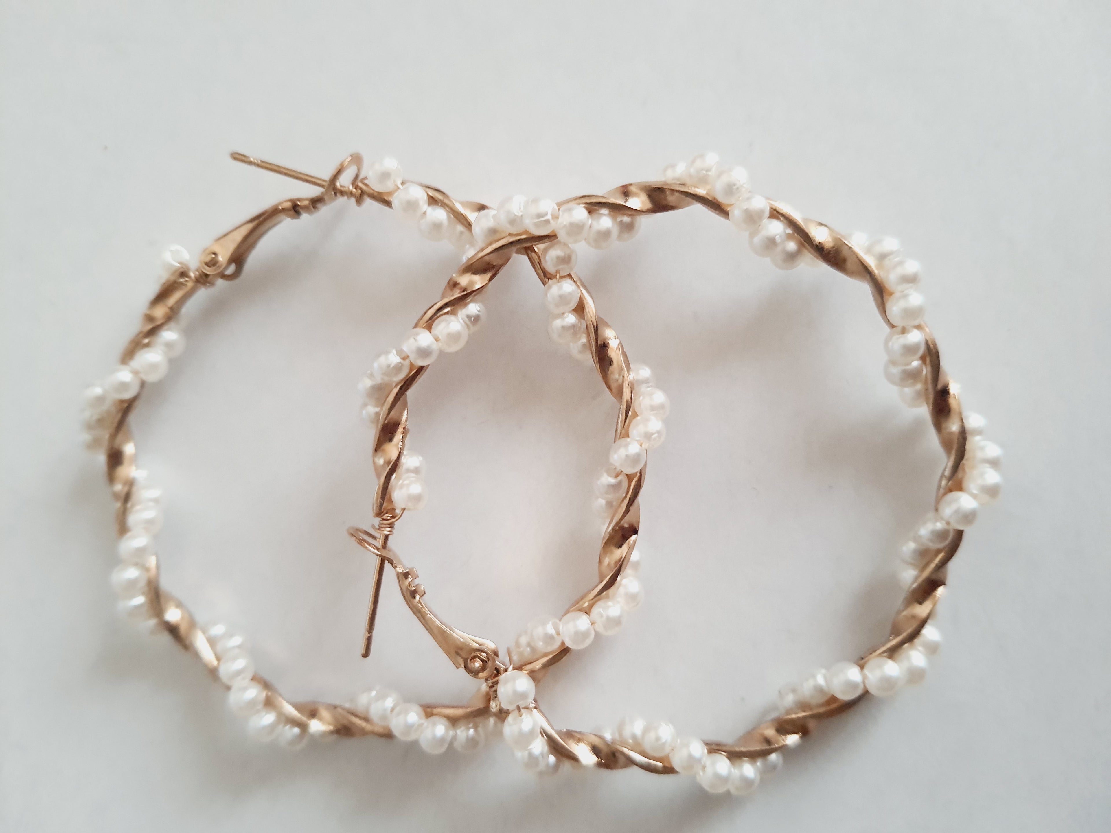 Duże kolczyki koła o średnicy 5 cm wykonane ze złotego, plecionego drutu, ozdobione syntetycznymi perełkami. Styl boho i romantyczny. Stal nierdzewna. Rouge Bizu.

