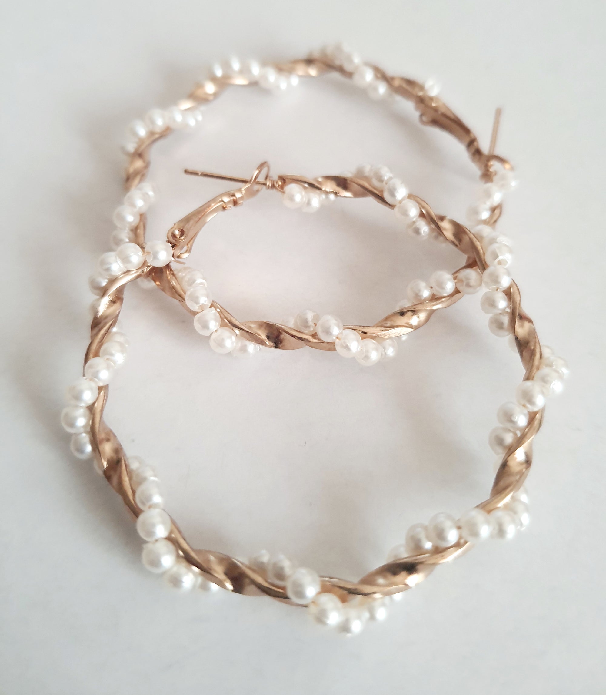 Duże kolczyki koła o średnicy 5 cm wykonane ze złotego, plecionego drutu, ozdobione syntetycznymi perełkami. Styl boho i romantyczny. Stal nierdzewna. Rouge Bizu.

