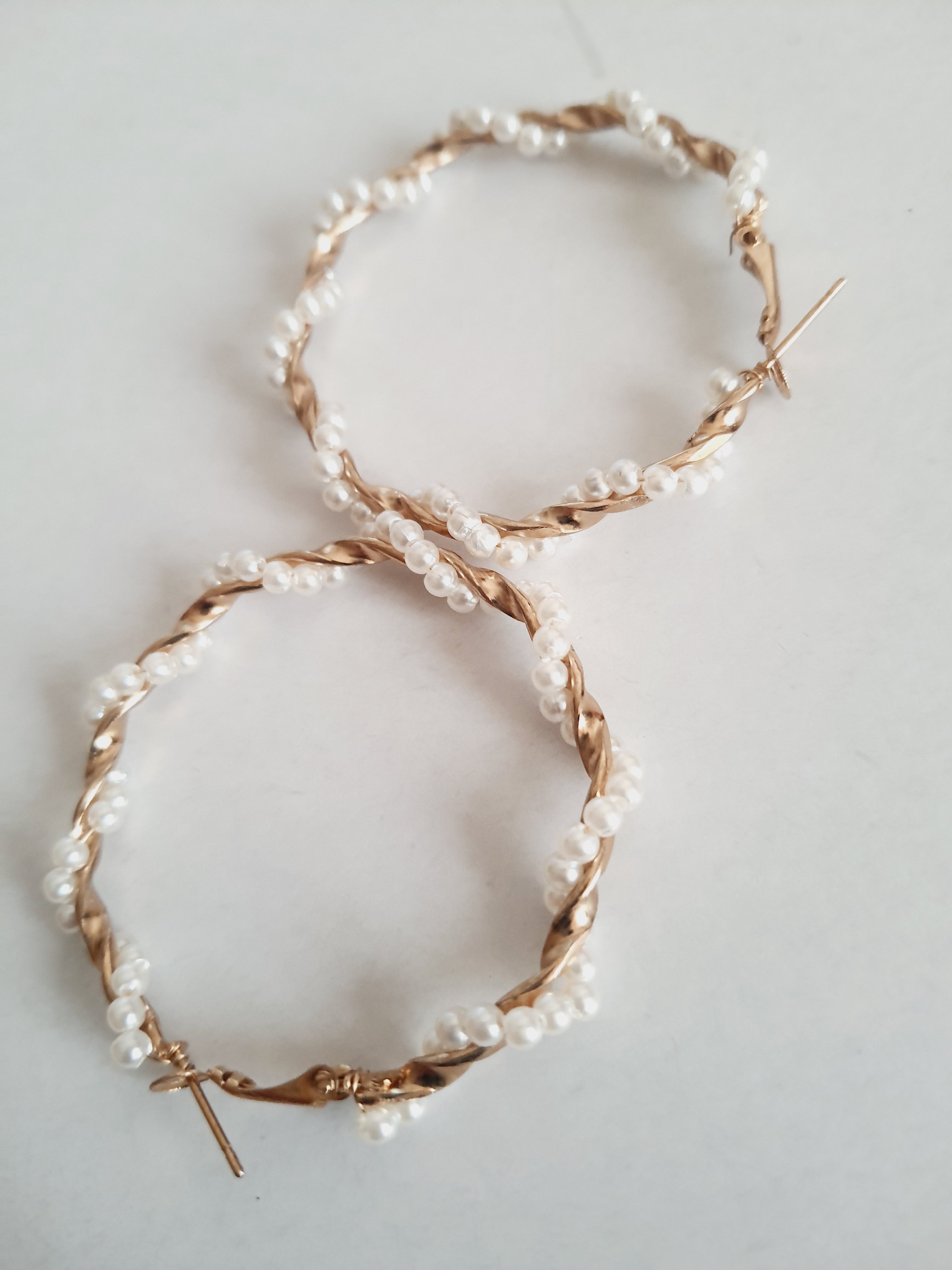 Duże kolczyki koła o średnicy 5 cm wykonane ze złotego, plecionego drutu, ozdobione syntetycznymi perełkami. Styl boho i romantyczny. Stal nierdzewna. Rouge Bizu.

