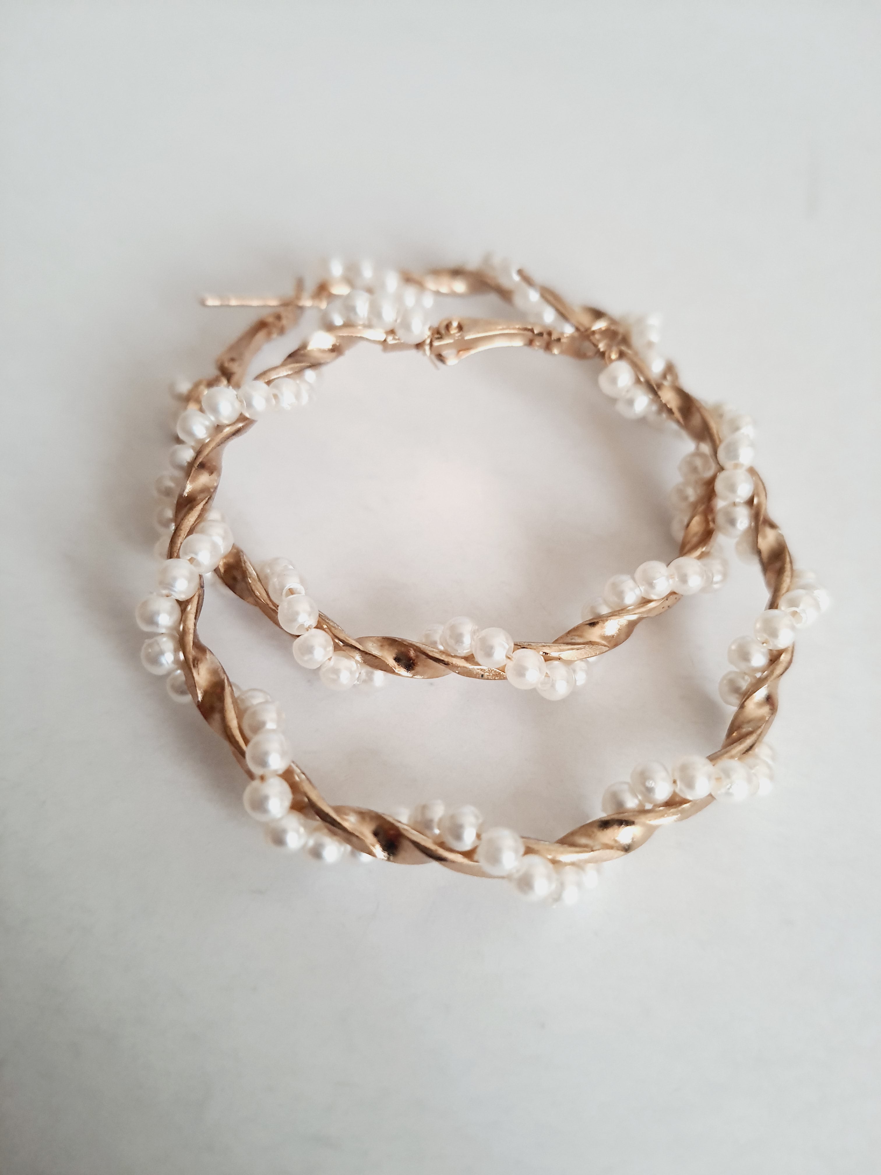 Duże kolczyki koła o średnicy 5 cm wykonane ze złotego, plecionego drutu, ozdobione syntetycznymi perełkami. Styl boho i romantyczny. Stal nierdzewna. Rouge Bizu.

