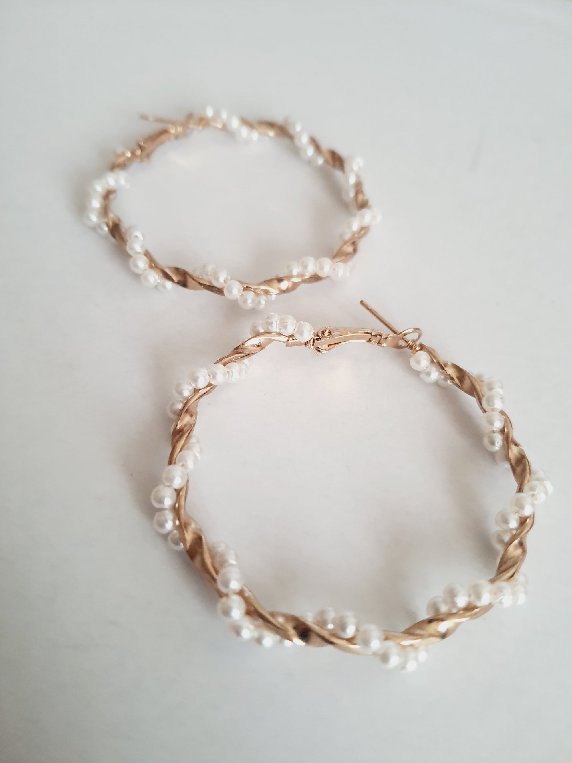 Duże kolczyki koła o średnicy 5 cm wykonane ze złotego, plecionego drutu, ozdobione syntetycznymi perełkami. Styl boho i romantyczny. Stal nierdzewna. Rouge Bizu.


