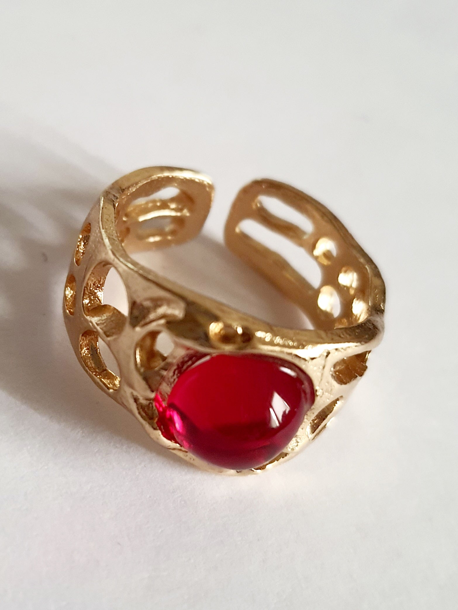 Złoty pierścionek artystyczny z czerwonym kaboszonem, stal nierdzewna, ażurowa forma, rozmiar 16 mm, elegancki i wyrazisty. Rouge Bizu.

