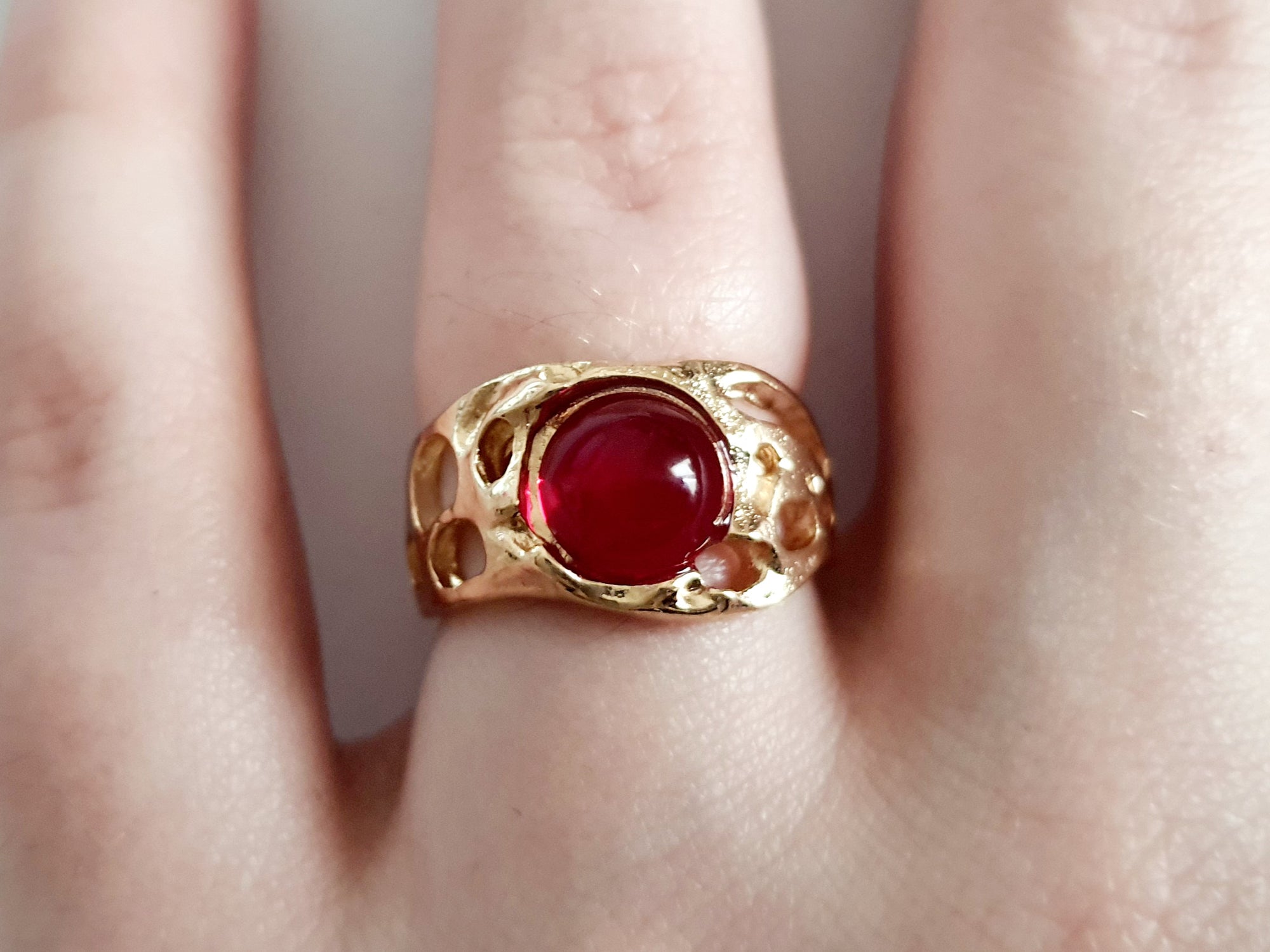Złoty pierścionek artystyczny z czerwonym kaboszonem, stal nierdzewna, ażurowa forma, rozmiar 16 mm, elegancki i wyrazisty. Rouge Bizu.

