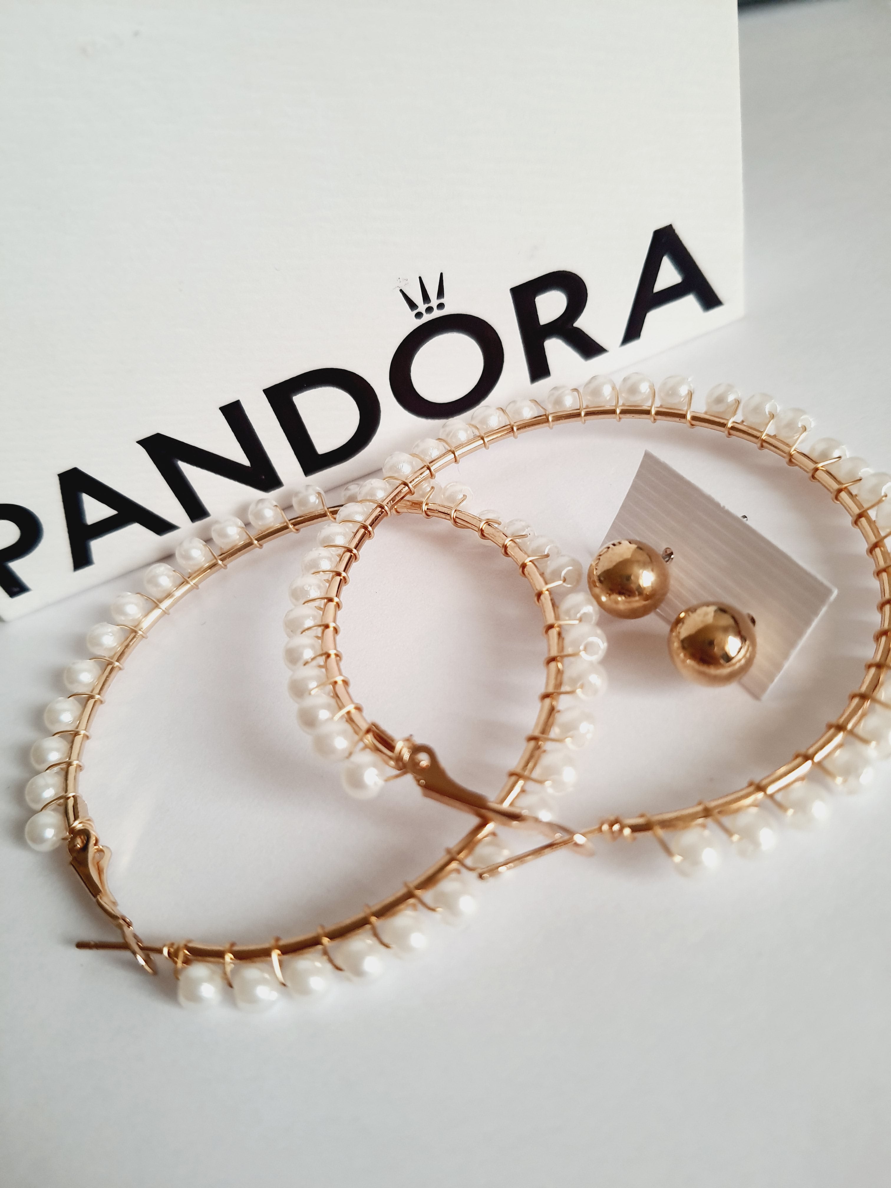 eleganckie kolczyki typu hoops o średnicy 6 cm, oplecione drobnymi perłami, obok złotych wkrętek. stal nierdzewna. rouge bizu
