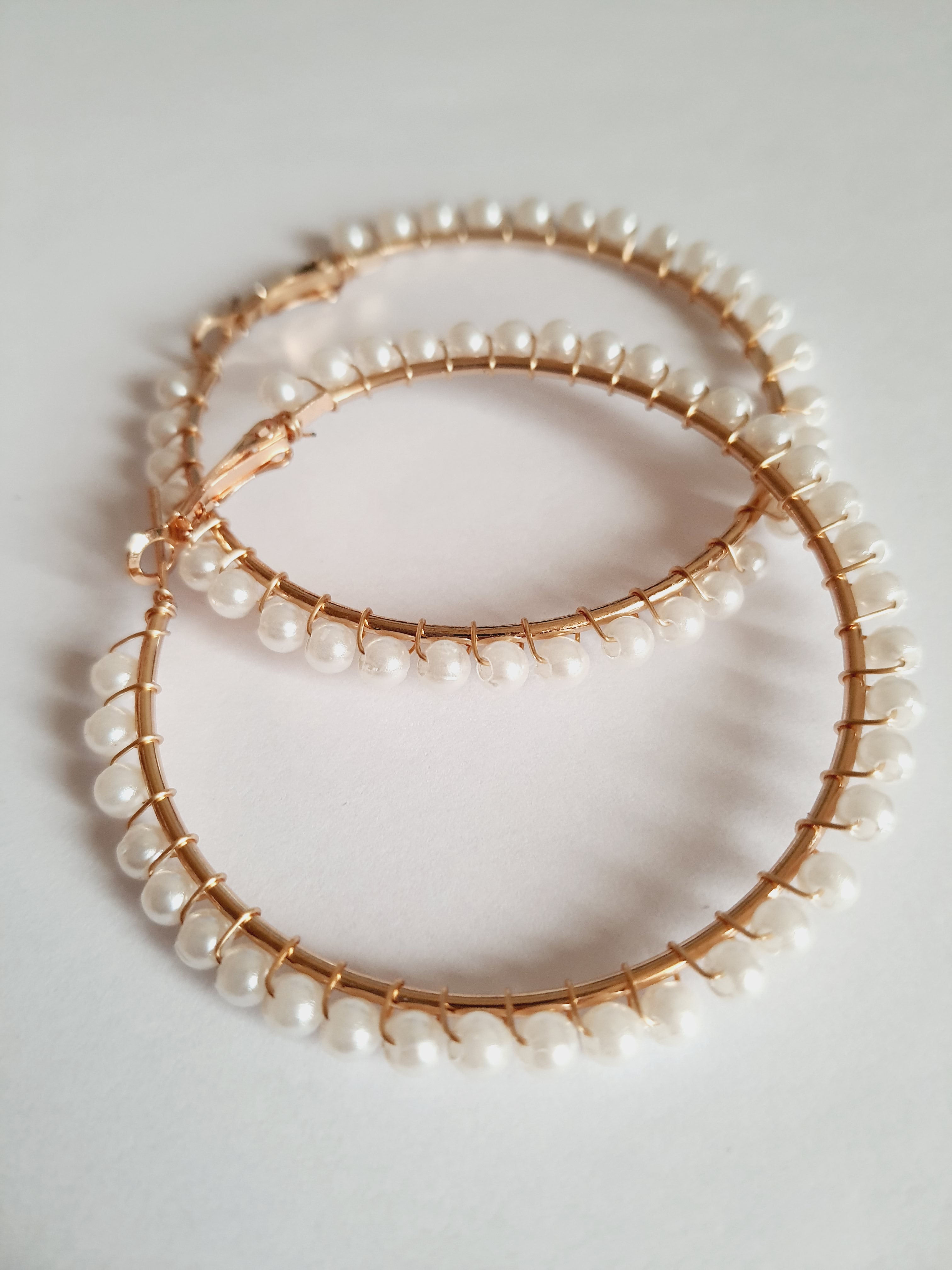 eleganckie kolczyki typu hoops o średnicy 6 cm, oplecione drobnymi perłami, obok złotych wkrętek. stal nierdzewna. rouge bizu
