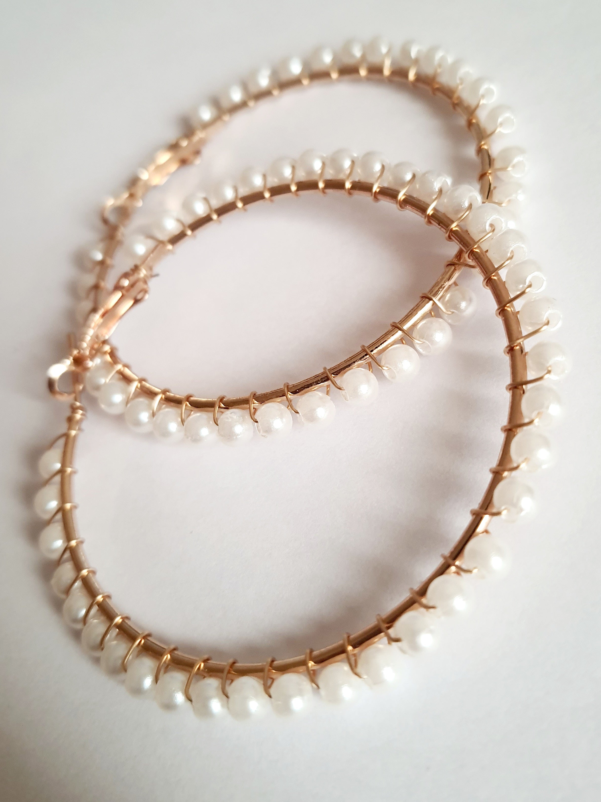 eleganckie kolczyki typu hoops o średnicy 6 cm, oplecione drobnymi perłami, obok złotych wkrętek. stal nierdzewna. rouge bizu

