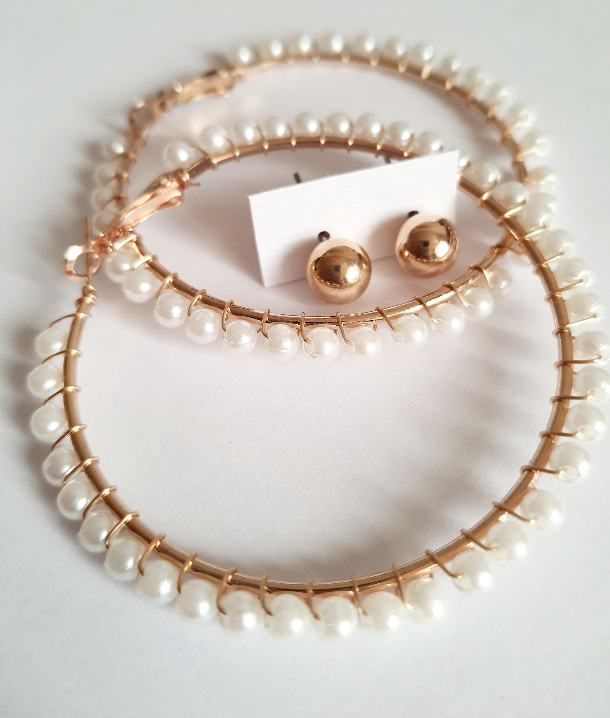 eleganckie kolczyki typu hoops o średnicy 6 cm, oplecione drobnymi perłami, obok złotych wkrętek. stal nierdzewna. rouge bizu
