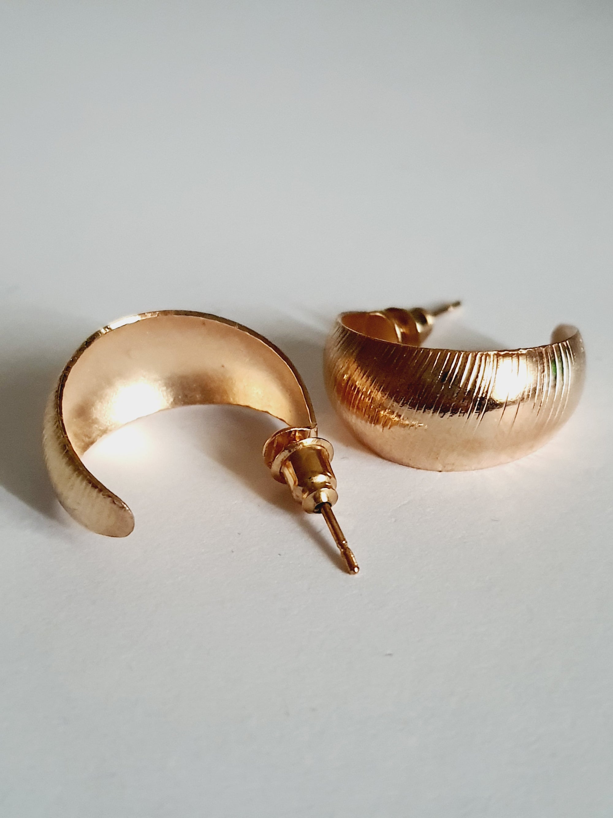 Złote kolczyki koła 2 cm wykonane ze stali chirurgicznej, błyszczące i eleganckie, leżące na jasnym tle

