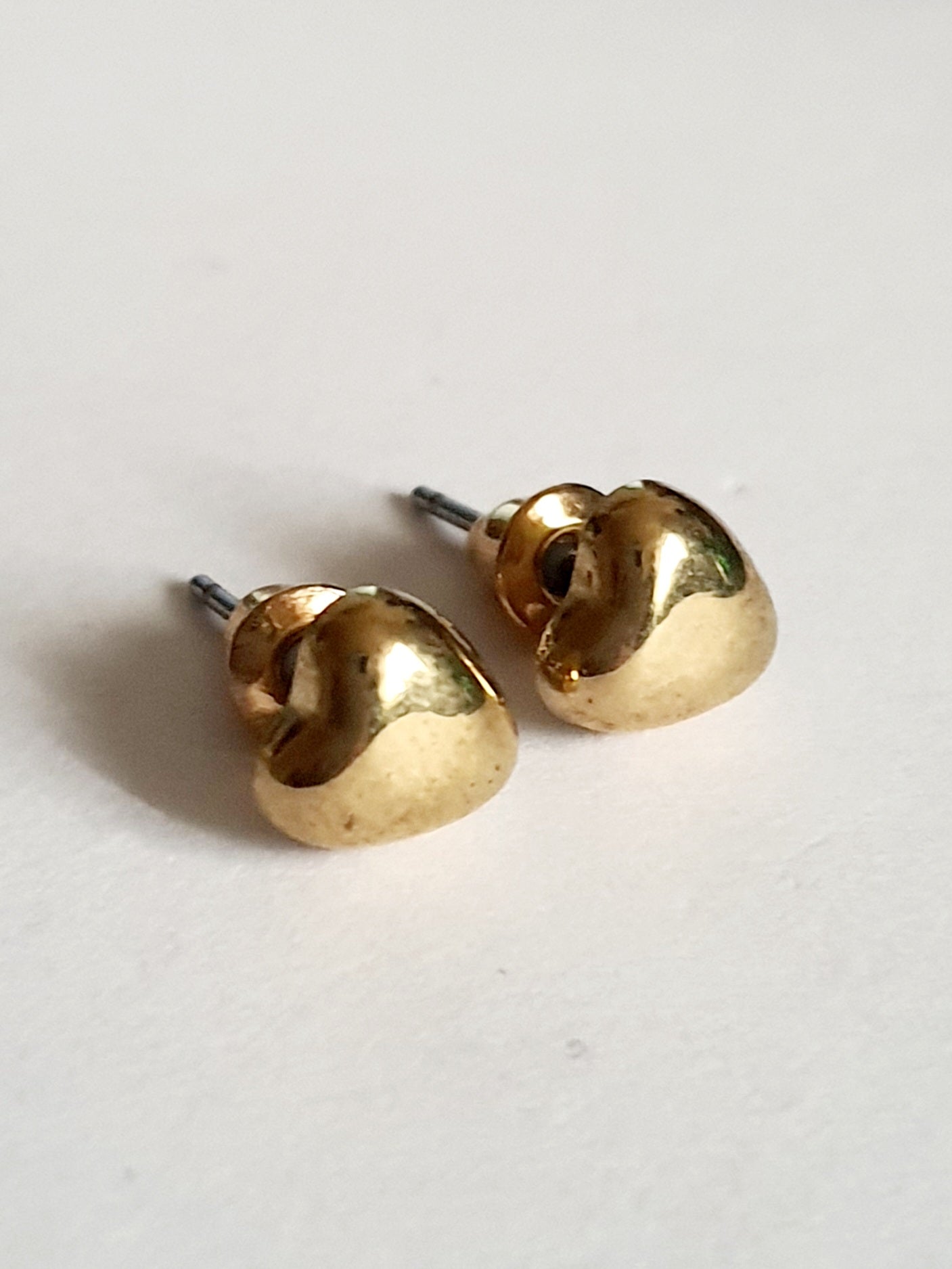 Złote kolczyki w kształcie małych serduszek 0,5 cm ze stali nierdzewnej, na białym tle

