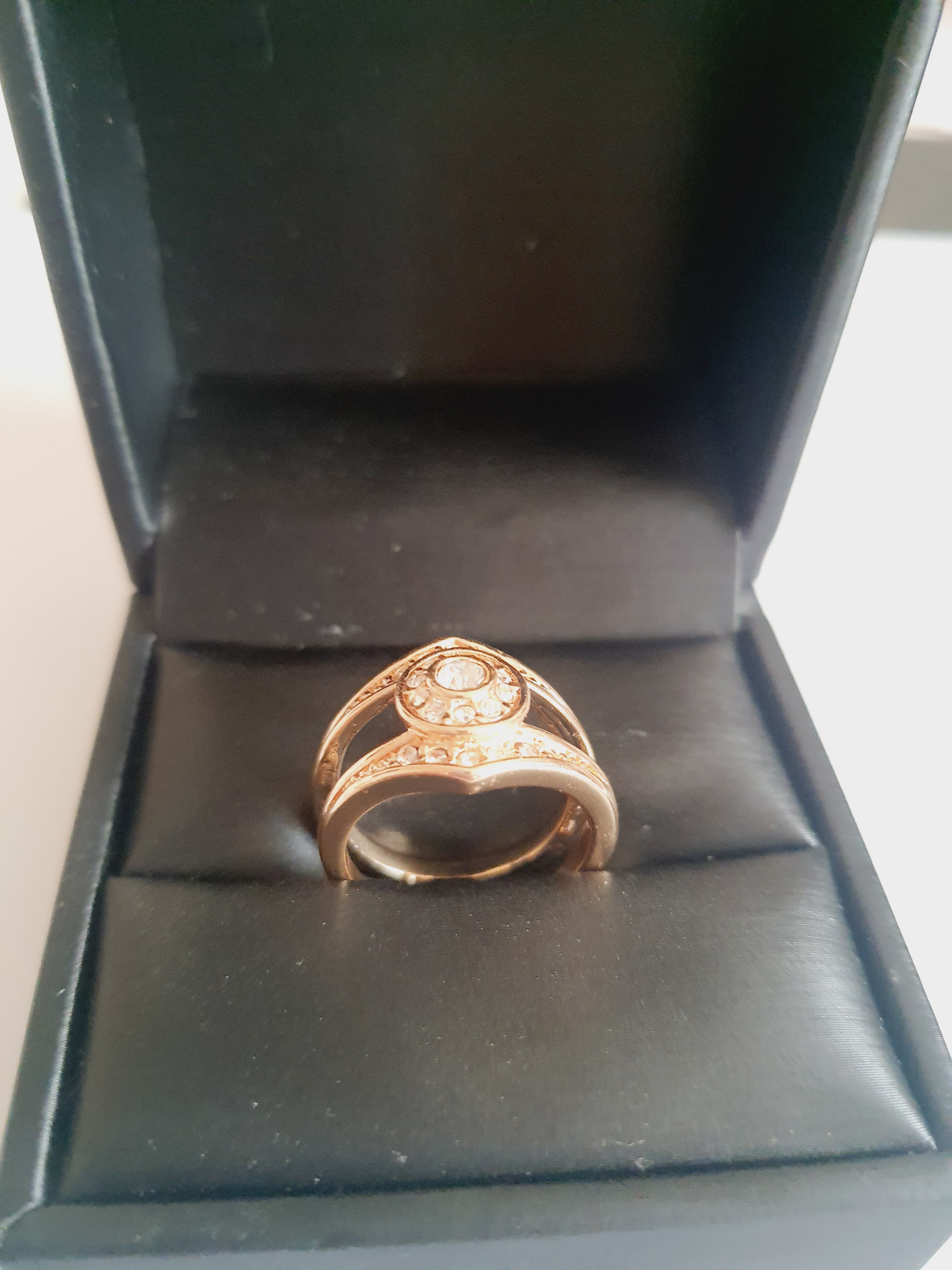 Złoty pierścionek ze stali chirurgicznej z okrągłym bezbarwnym kryształem w centrum, otoczonym drobnymi cyrkoniami. Podwójna obrączka, klasyczny styl. Rozmiar 16 mm. Rouge Bizu.

