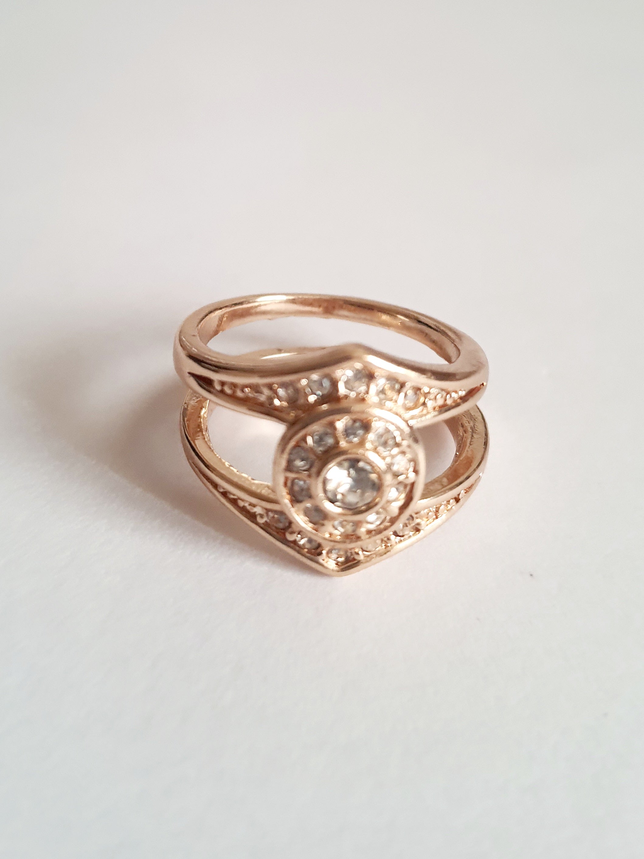 Złoty pierścionek ze stali chirurgicznej z okrągłym bezbarwnym kryształem w centrum, otoczonym drobnymi cyrkoniami. Podwójna obrączka, klasyczny styl. Rozmiar 16 mm. Rouge Bizu.

