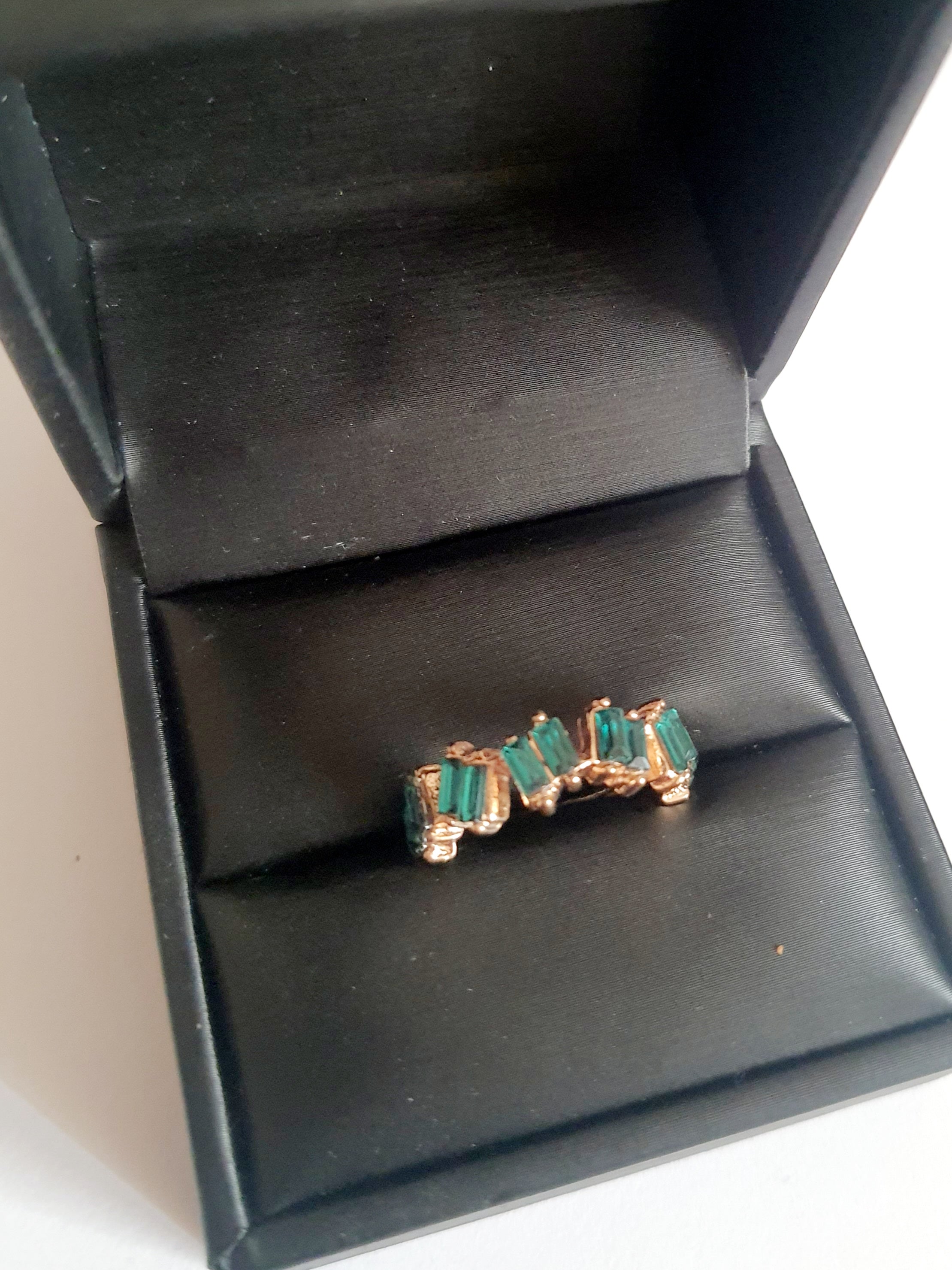 Pierścionek ze stali chirurgicznej w kolorze żółtego złota, ozdobiony szmaragdowymi kryształami typu baguette w górnej części obrączki. Styl minimalistyczny glamour. Rozmiar 18 mm. Rouge Bizu.

