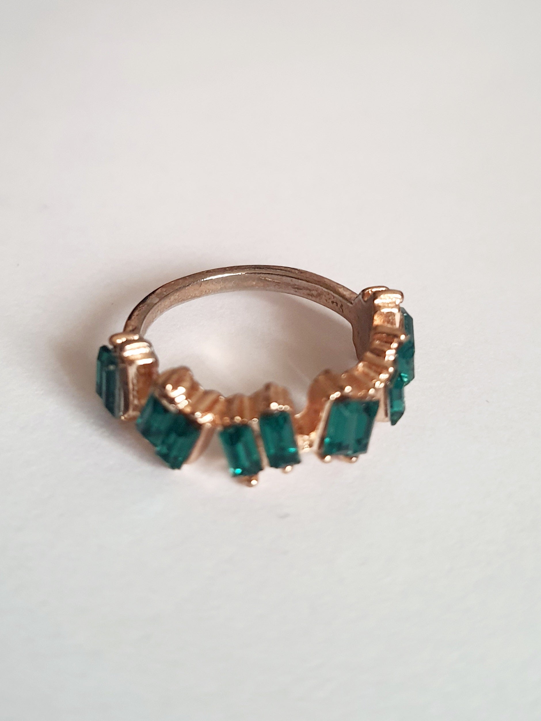 Pierścionek ze stali chirurgicznej w kolorze żółtego złota, ozdobiony szmaragdowymi kryształami typu baguette w górnej części obrączki. Styl minimalistyczny glamour. Rozmiar 18 mm. Rouge Bizu.

