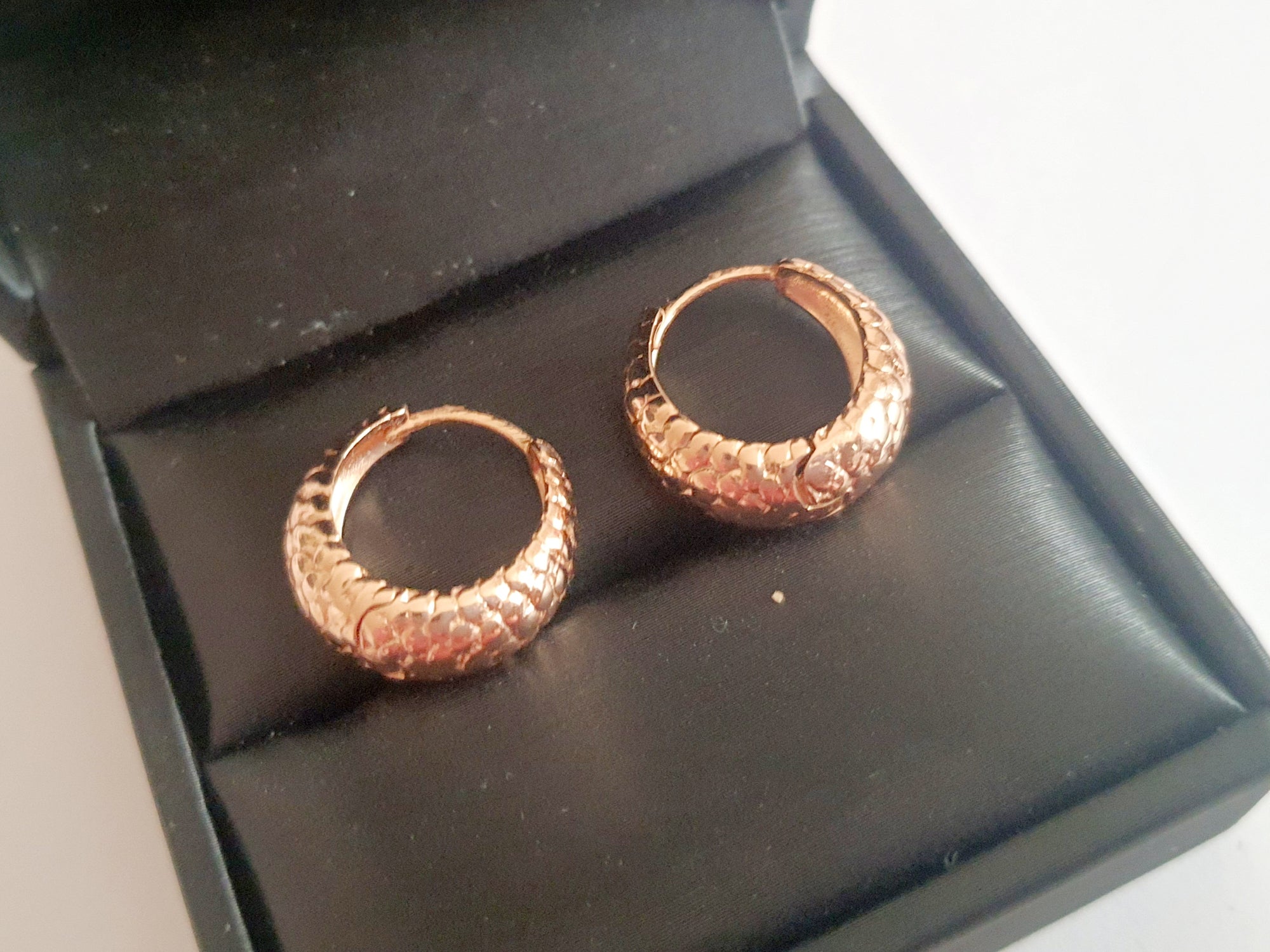 Kolczyki huggie ze stali chirurgicznej w kolorze różowego złota, z młotkowaną fakturą, średnica 1,2 cm. Klasyczny styl z fakturowanym wykończeniem. Rouge Bizu.

