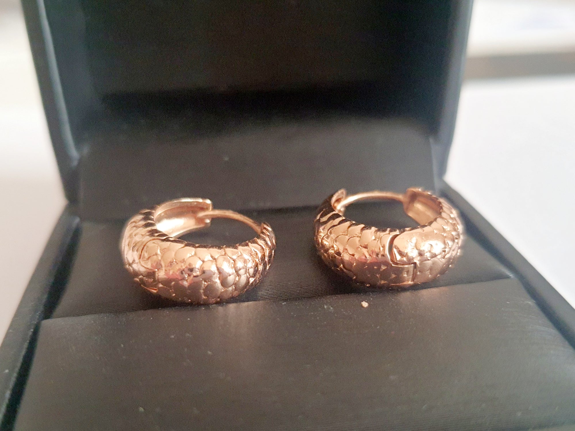 Kolczyki huggie ze stali chirurgicznej w kolorze różowego złota, z młotkowaną fakturą, średnica 1,2 cm. Klasyczny styl z fakturowanym wykończeniem. Rouge Bizu.

