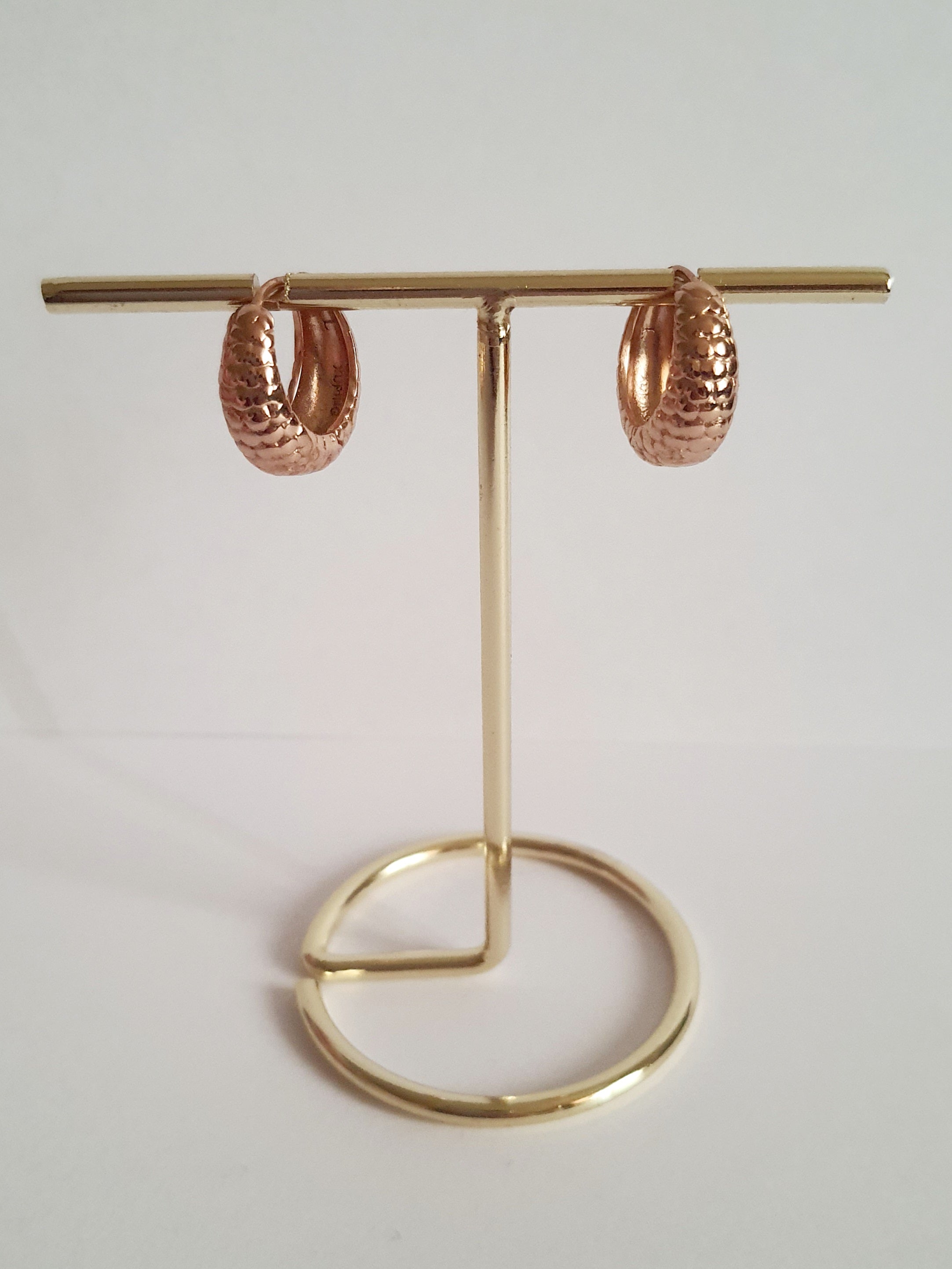 Kolczyki huggie ze stali chirurgicznej w kolorze różowego złota, z młotkowaną fakturą, średnica 1,2 cm. Klasyczny styl z fakturowanym wykończeniem. Rouge Bizu.

