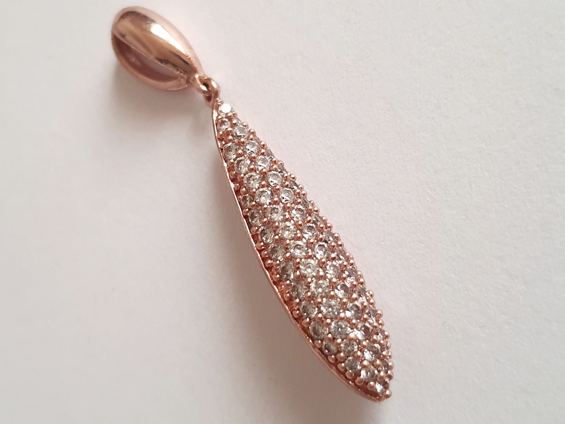 Wisiorek ze stali chirurgicznej w kolorze różowego złota, długość 4 cm, w kształcie kropli wysadzanej drobnymi cyrkoniami. Elegancki połysk, nowoczesny glamour. Rouge Bizu.

