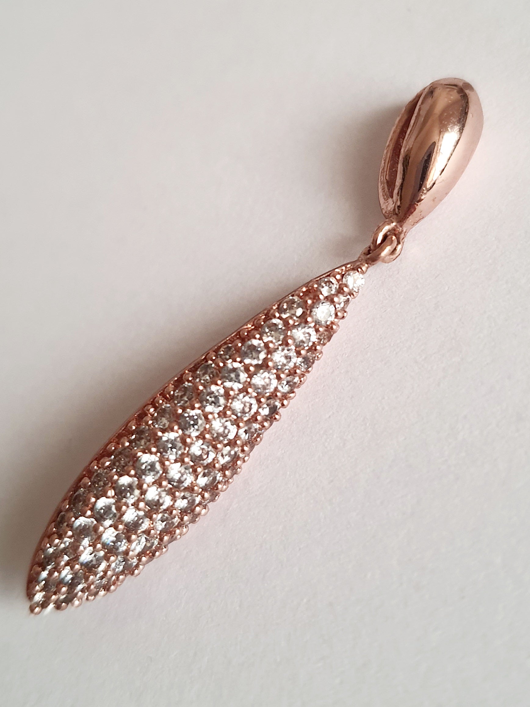 Wisiorek ze stali chirurgicznej w kolorze różowego złota, długość 4 cm, w kształcie kropli wysadzanej drobnymi cyrkoniami. Elegancki połysk, nowoczesny glamour. Rouge Bizu.

