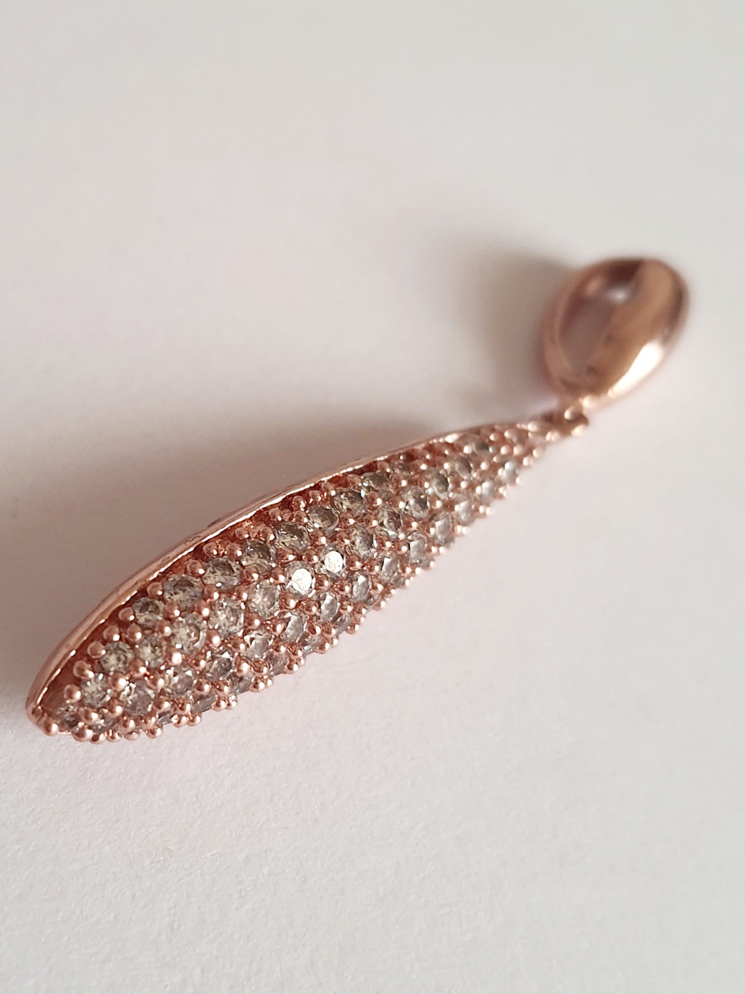 Wisiorek ze stali chirurgicznej w kolorze różowego złota, długość 4 cm, w kształcie kropli wysadzanej drobnymi cyrkoniami. Elegancki połysk, nowoczesny glamour. Rouge Bizu.

