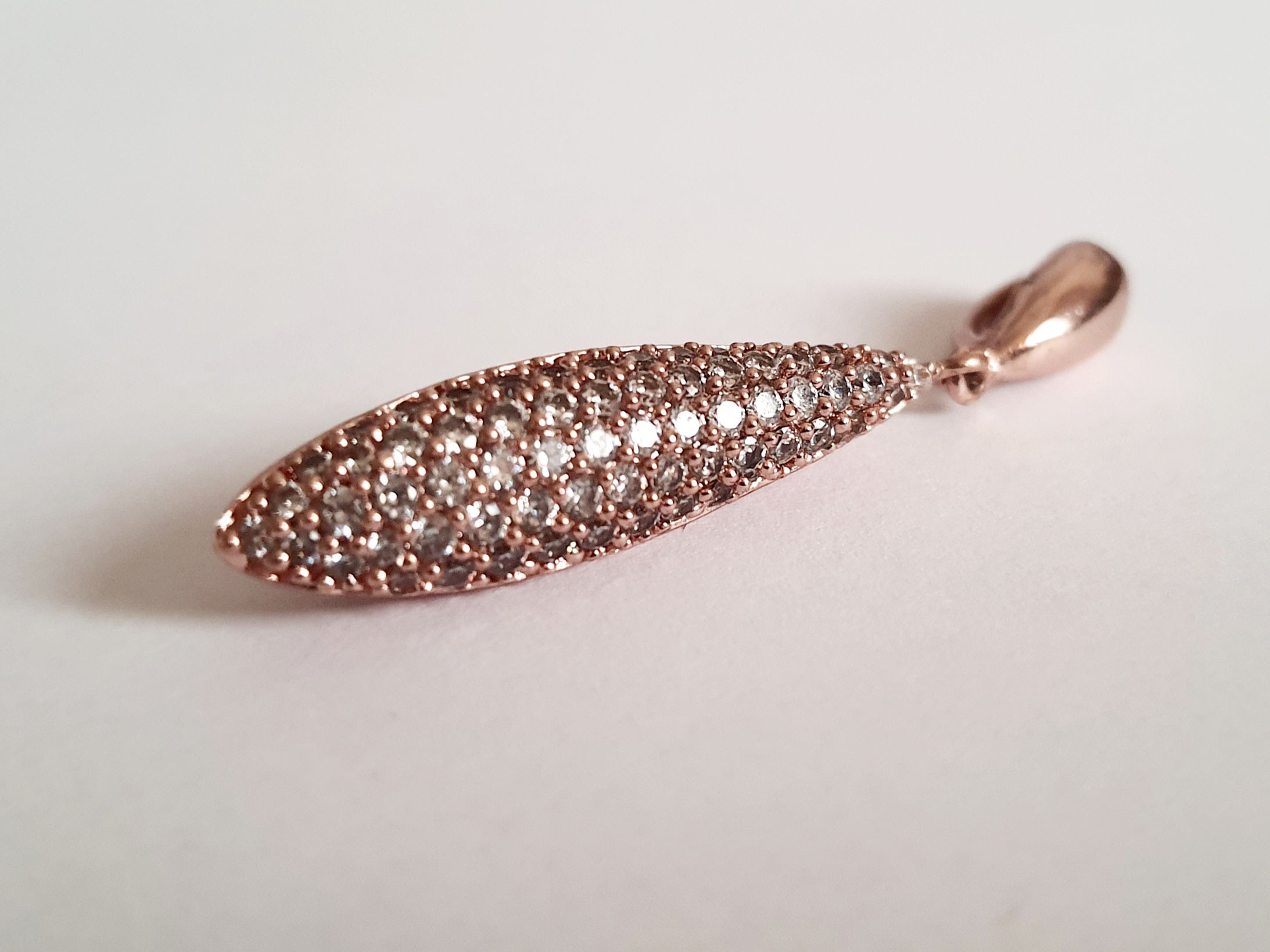 Wisiorek ze stali chirurgicznej w kolorze różowego złota, długość 4 cm, w kształcie kropli wysadzanej drobnymi cyrkoniami. Elegancki połysk, nowoczesny glamour. Rouge Bizu.

