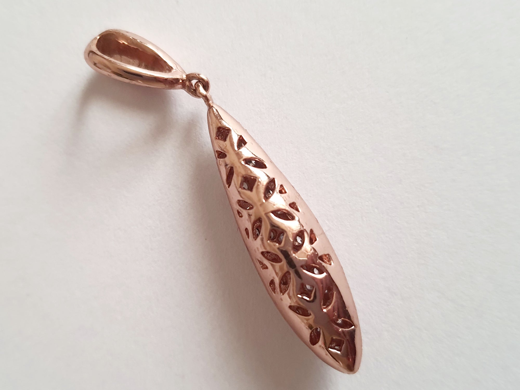 Wisiorek ze stali chirurgicznej w kolorze różowego złota, długość 4 cm, w kształcie kropli wysadzanej drobnymi cyrkoniami. Elegancki połysk, nowoczesny glamour. Rouge Bizu.

