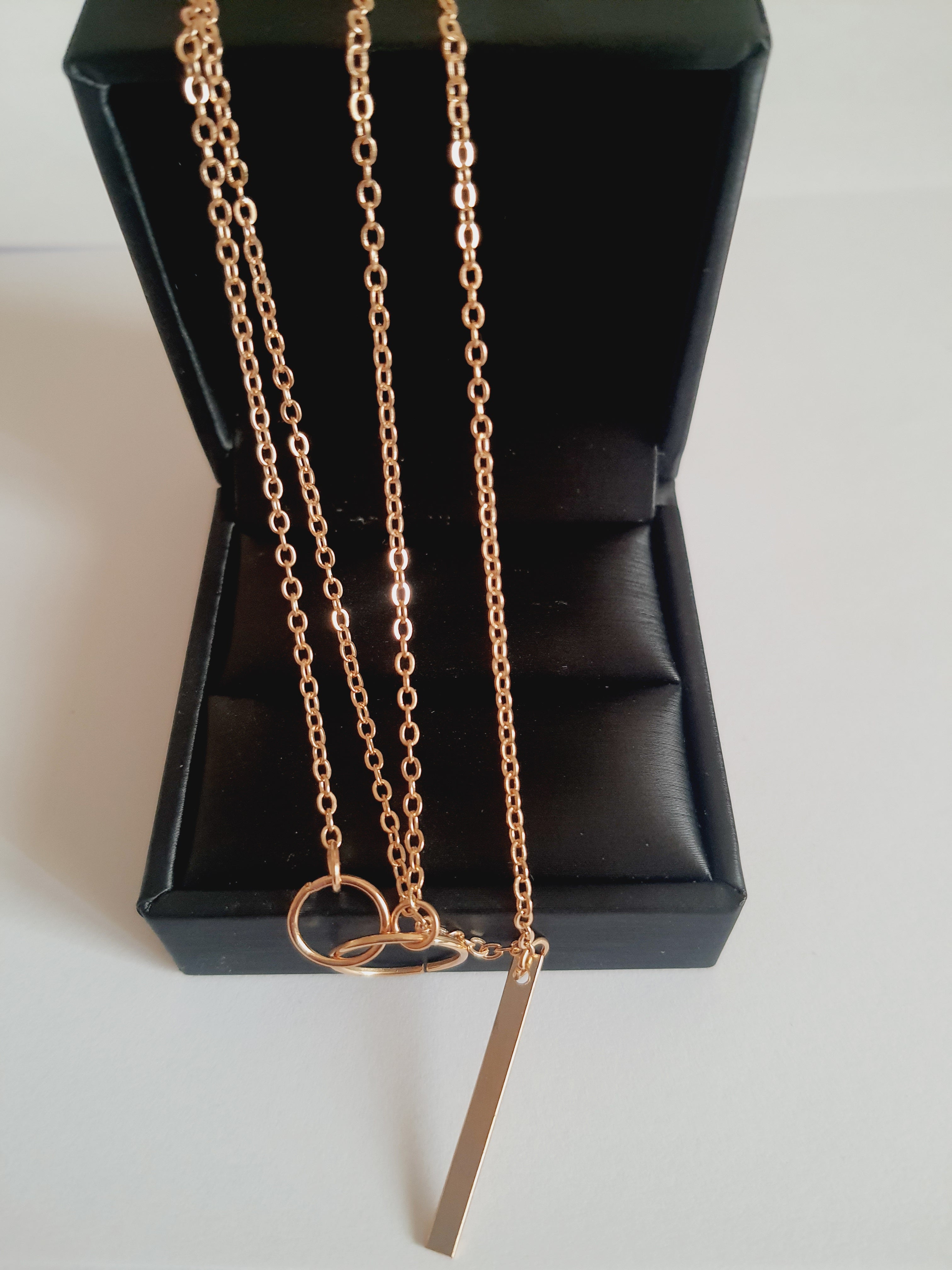 Przewlekany łańcuszek celebrytka ze stali chirurgicznej w kolorze żółtego złota, z dwiema obręczami i prostą podłużną zawieszką. Długość maksymalna 55 cm. Minimalistyczny styl. Rouge Bizu.

