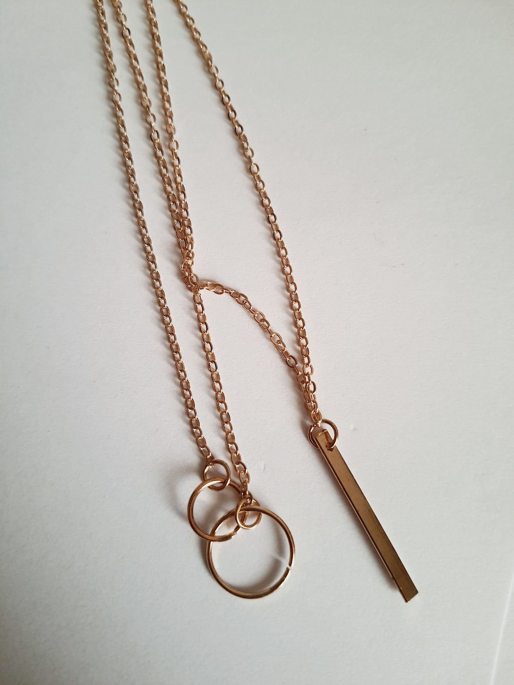 Przewlekany łańcuszek celebrytka ze stali chirurgicznej w kolorze żółtego złota, z dwiema obręczami i prostą podłużną zawieszką. Długość maksymalna 55 cm. Minimalistyczny styl. Rouge Bizu.

