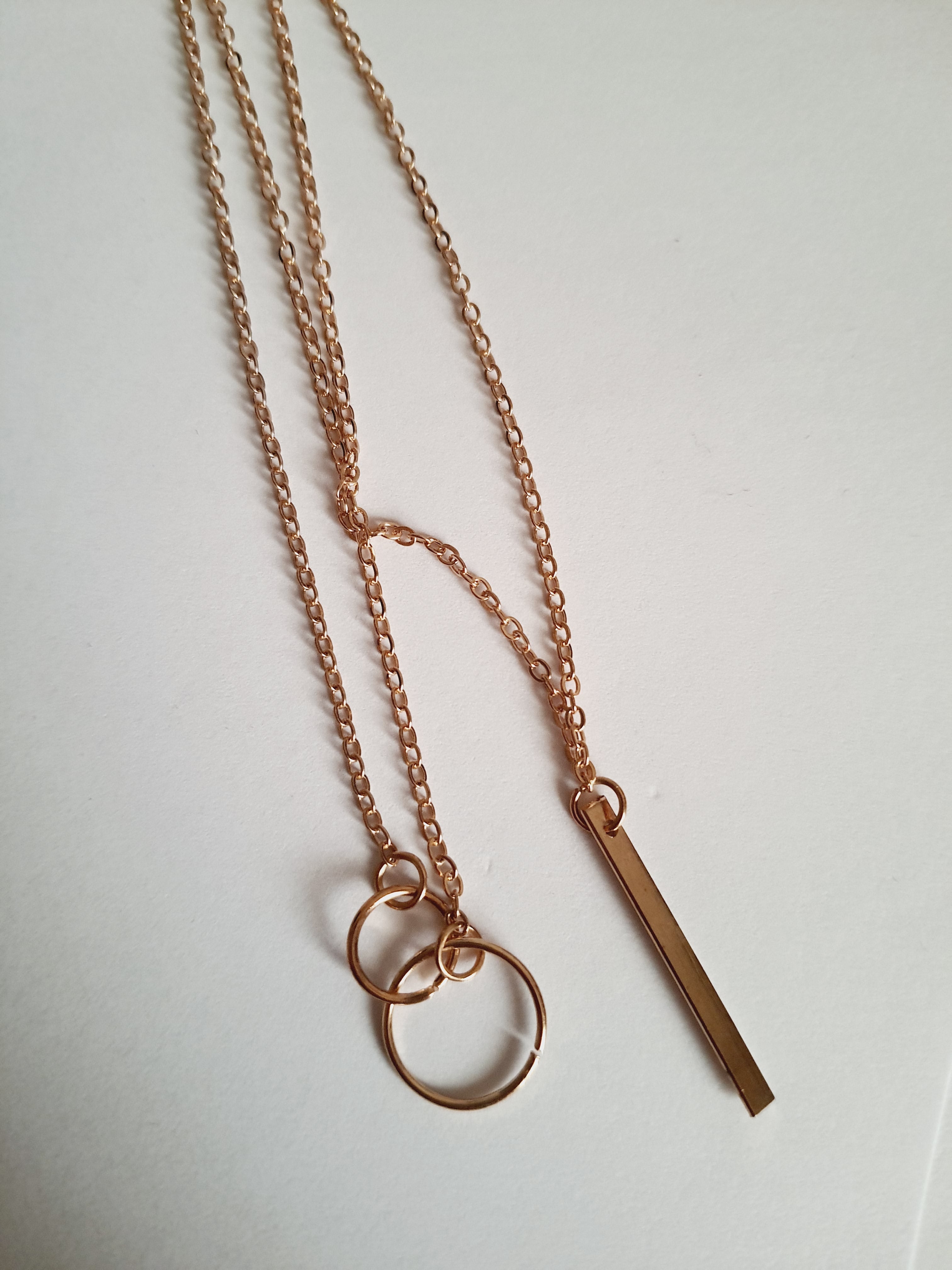 Przewlekany łańcuszek celebrytka ze stali chirurgicznej w kolorze żółtego złota, z dwiema obręczami i prostą podłużną zawieszką. Długość maksymalna 55 cm. Minimalistyczny styl. Rouge Bizu.

