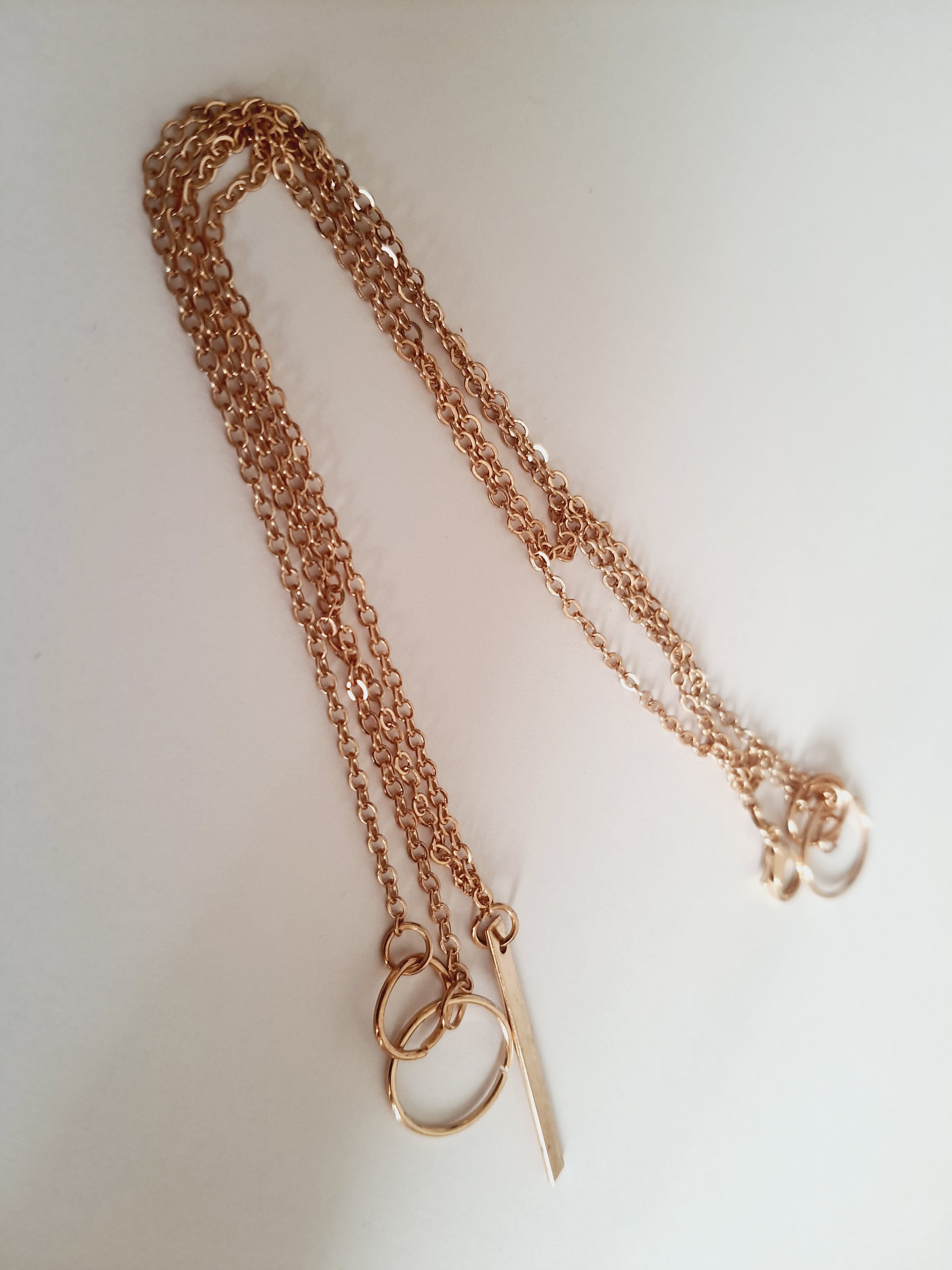 Przewlekany łańcuszek celebrytka ze stali chirurgicznej w kolorze żółtego złota, z dwiema obręczami i prostą podłużną zawieszką. Długość maksymalna 55 cm. Minimalistyczny styl. Rouge Bizu.

