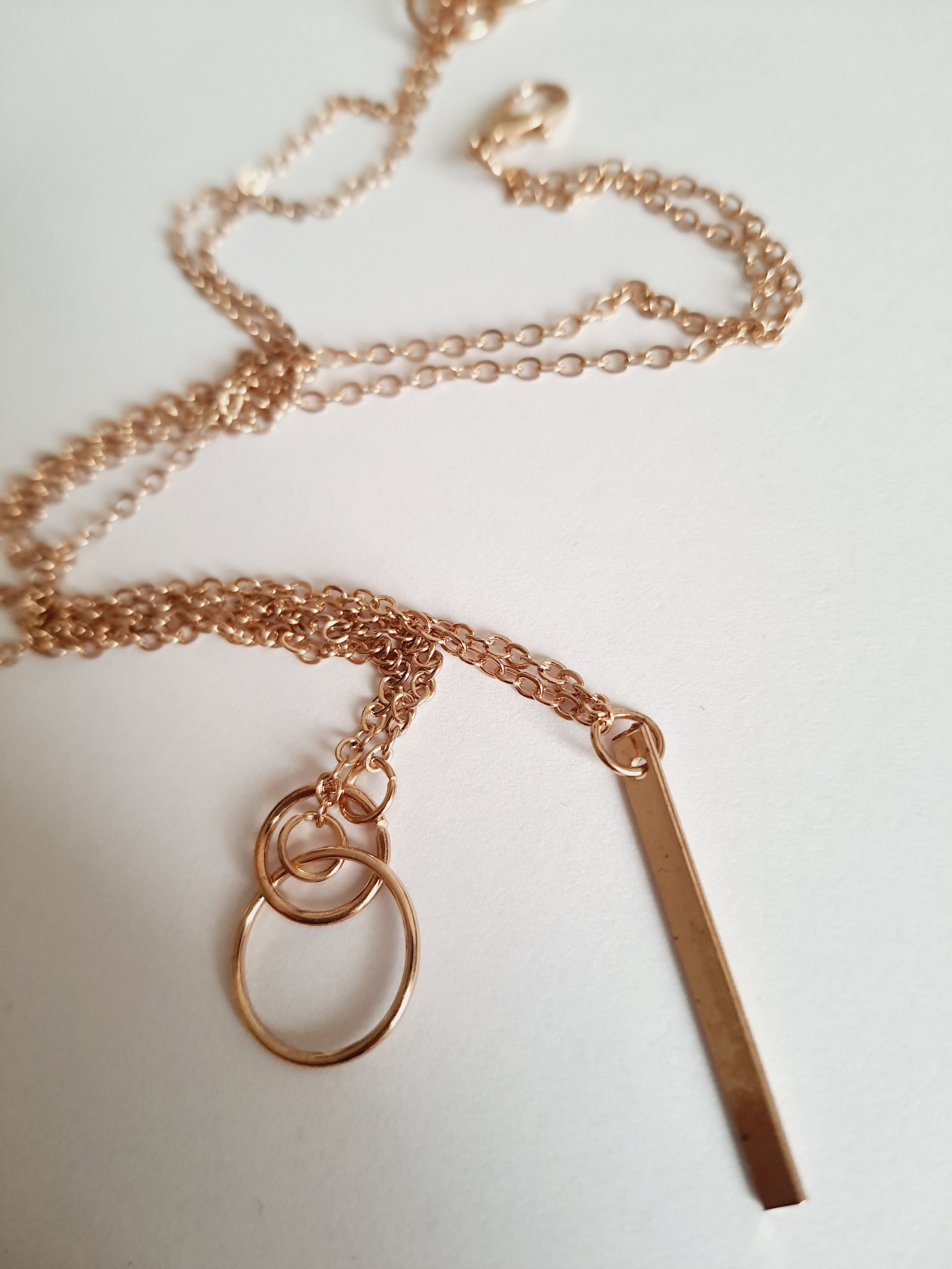 Przewlekany łańcuszek celebrytka ze stali chirurgicznej w kolorze żółtego złota, z dwiema obręczami i prostą podłużną zawieszką. Długość maksymalna 55 cm. Minimalistyczny styl. Rouge Bizu.

