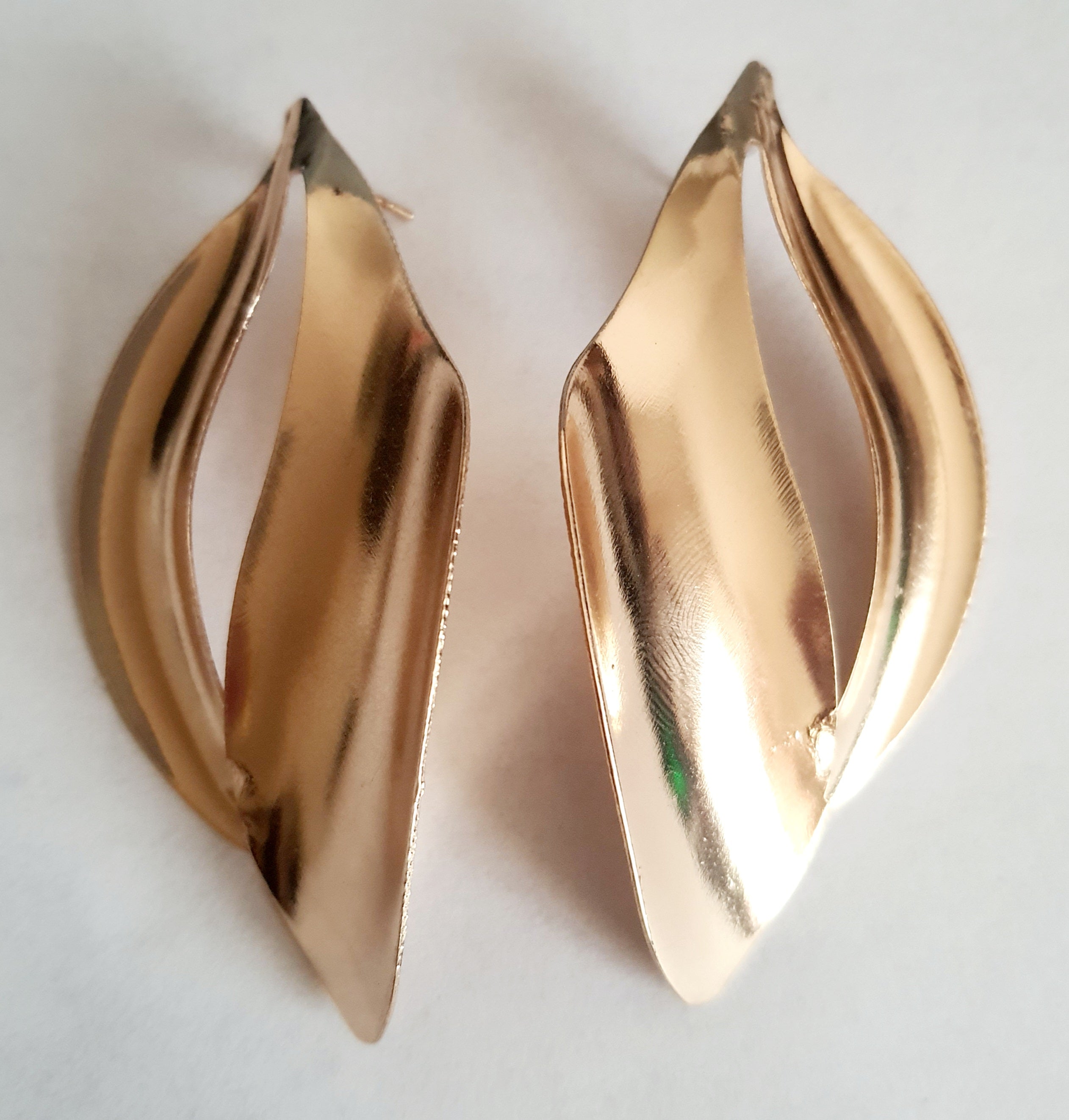 Kolczyki ze stali nierdzewnej w kolorze złotym o rzeźbiarskim kształcie fal. Długość 7 cm, na wkrętki. Eleganckie, lekkie i nowoczesne. Rouge Bizu.

