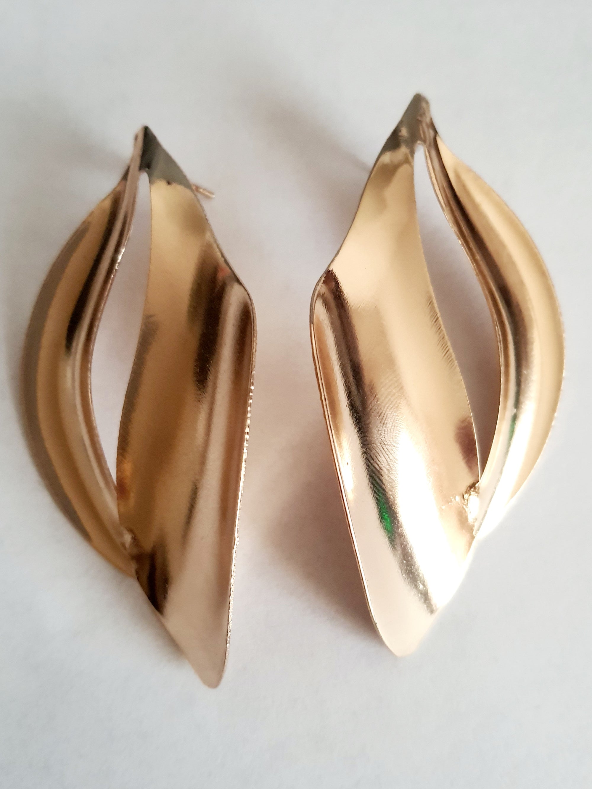 Kolczyki ze stali nierdzewnej w kolorze złotym o rzeźbiarskim kształcie fal. Długość 7 cm, na wkrętki. Eleganckie, lekkie i nowoczesne. Rouge Bizu.

