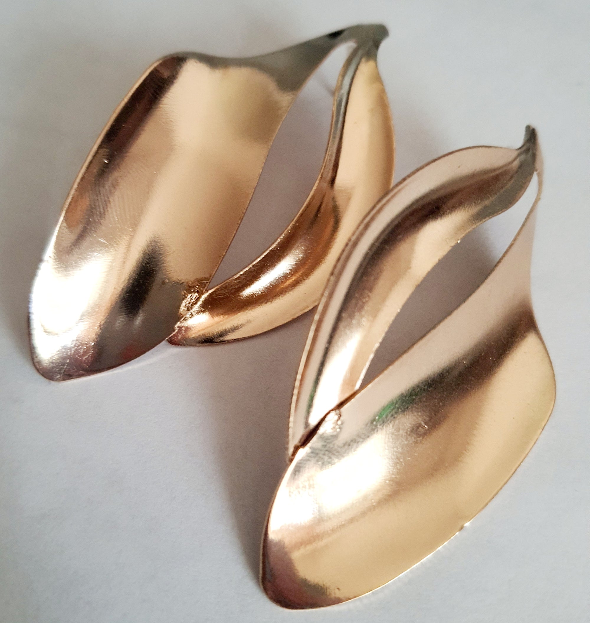 Kolczyki ze stali nierdzewnej w kolorze złotym o rzeźbiarskim kształcie fal. Długość 7 cm, na wkrętki. Eleganckie, lekkie i nowoczesne. Rouge Bizu.

