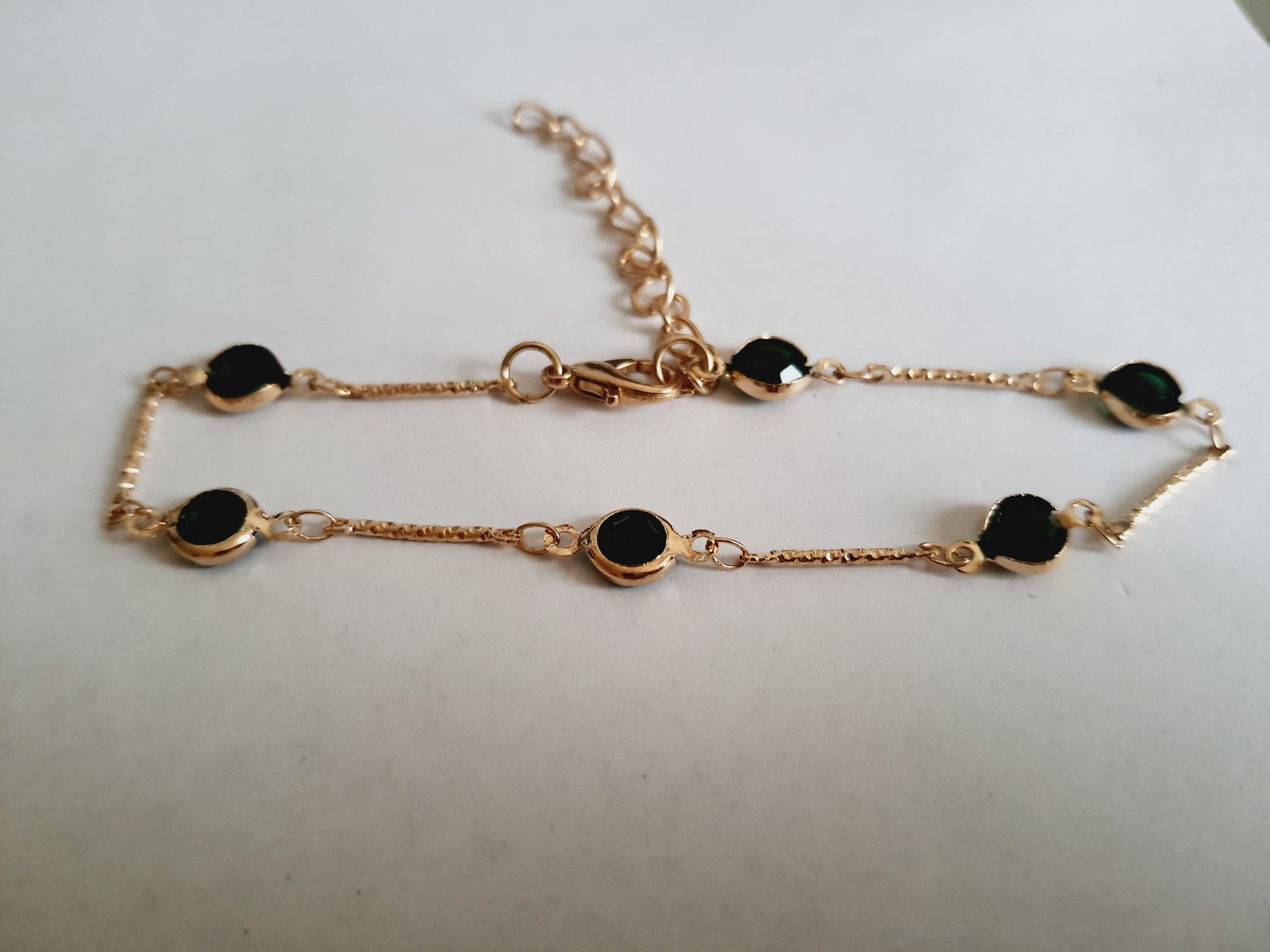 Bransoletka z szmaragdowymi cyrkoniami, złoty łańcuszek, regulowana długość 20–25 cm. Delikatna, elegancka, klasyczna biżuteria ze stali nierdzewnej. Rouge Bizu.


