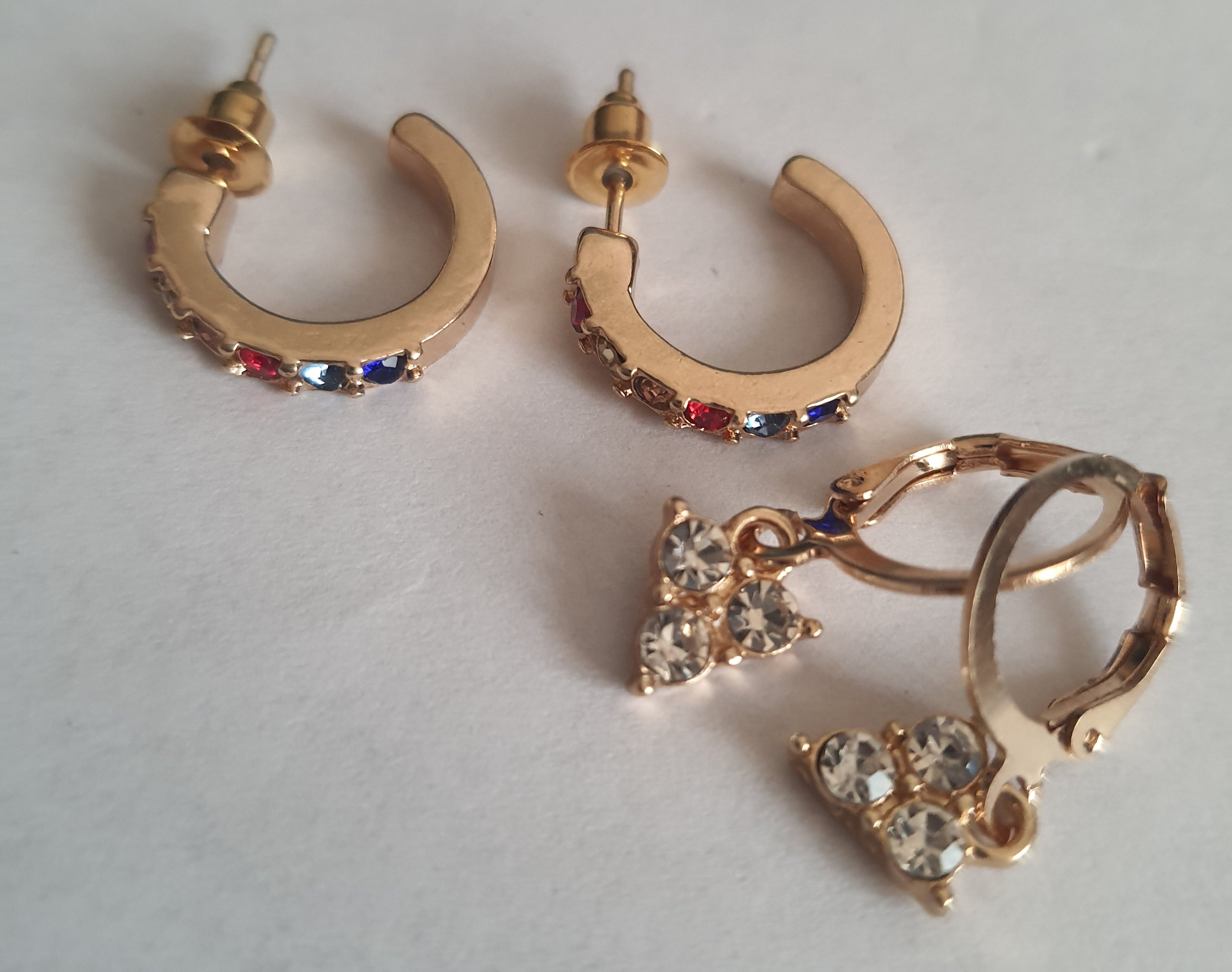 Zestaw 2 par kolczyków: złote kółka z kolorowymi cyrkoniami (1 cm) i wiszące kolczyki z trzema cyrkoniami (2 cm), biżuteria Rouge Bizu.

