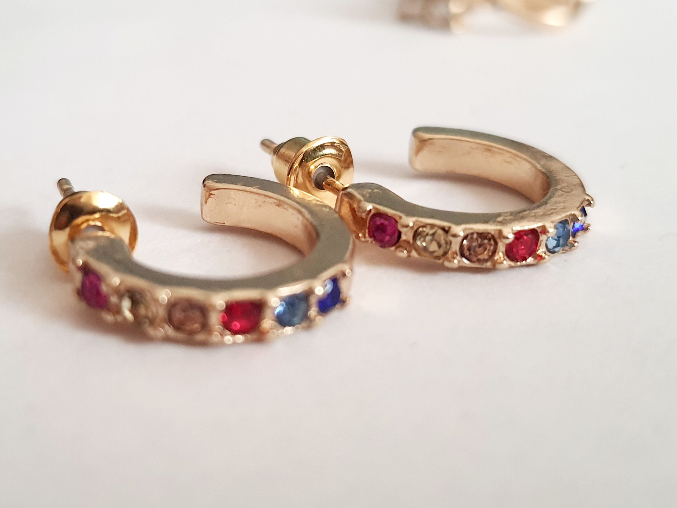 Zestaw 2 par kolczyków: złote kółka z kolorowymi cyrkoniami (1 cm) i wiszące kolczyki z trzema cyrkoniami (2 cm), biżuteria Rouge Bizu.

